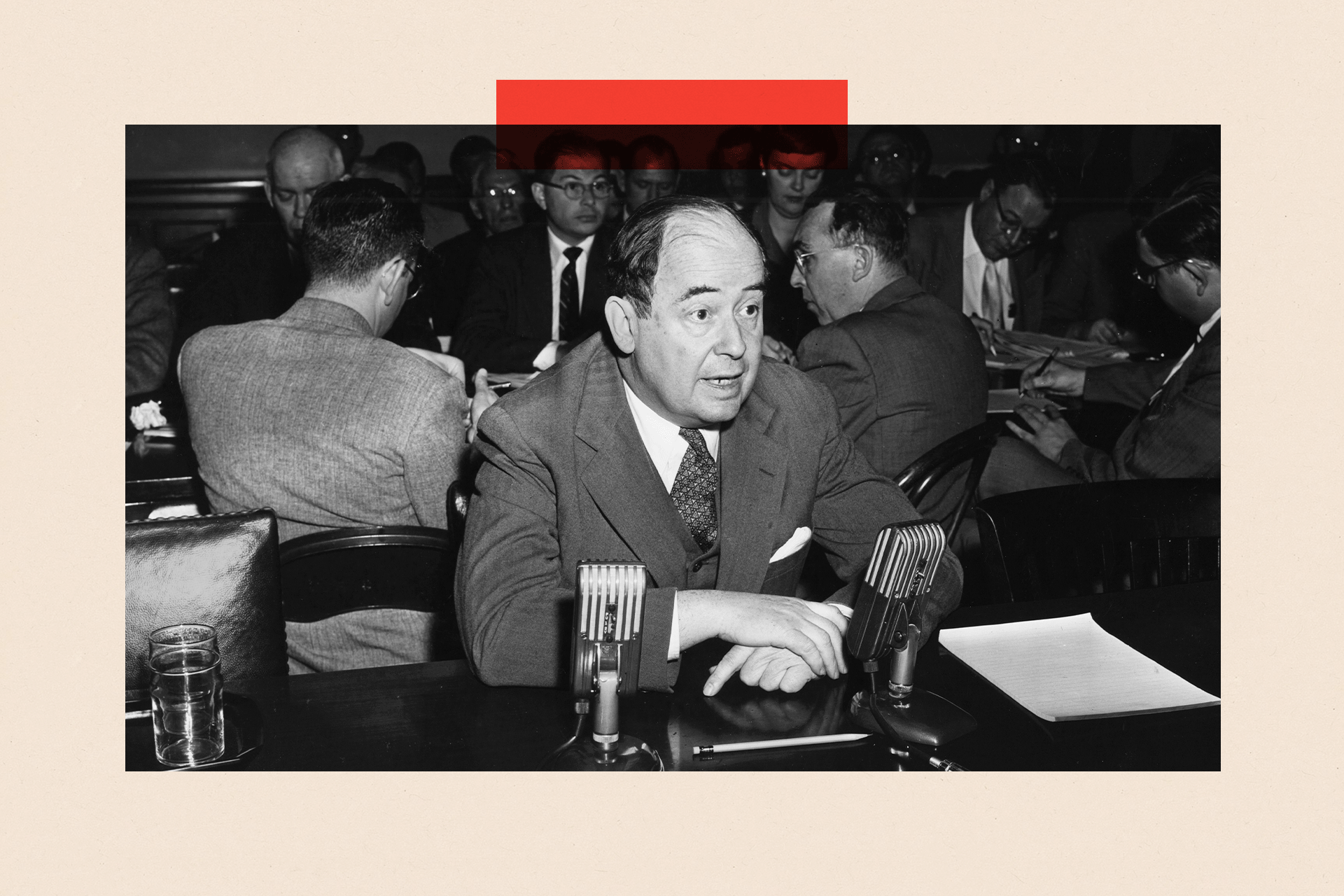 Black and white image of John von Neumann wearing a suit and sitting at a table