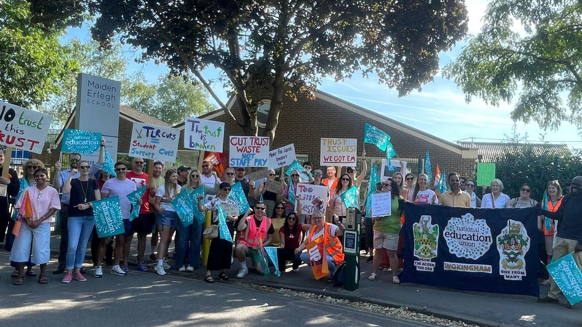 Several teachers striking with pickets outside a school