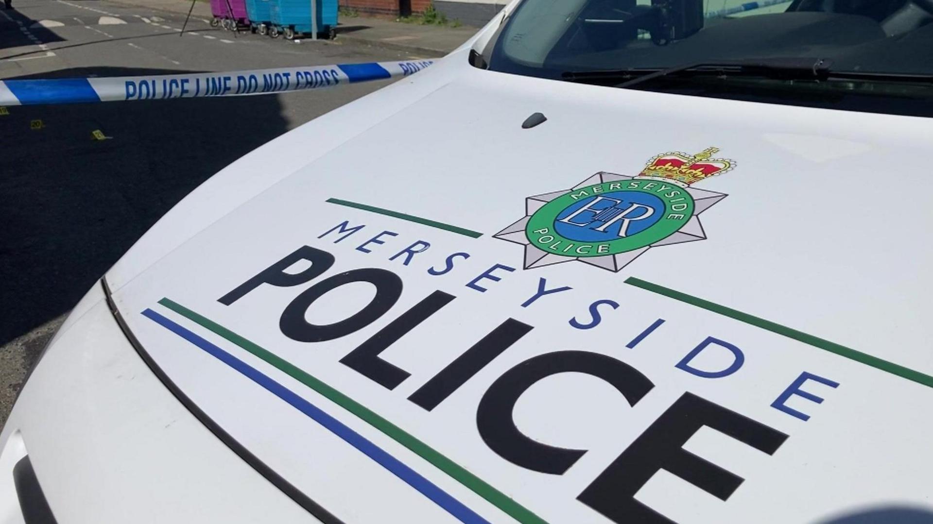 Close-up image of the bonnet of a white police car with Merseyside Police insignia across it