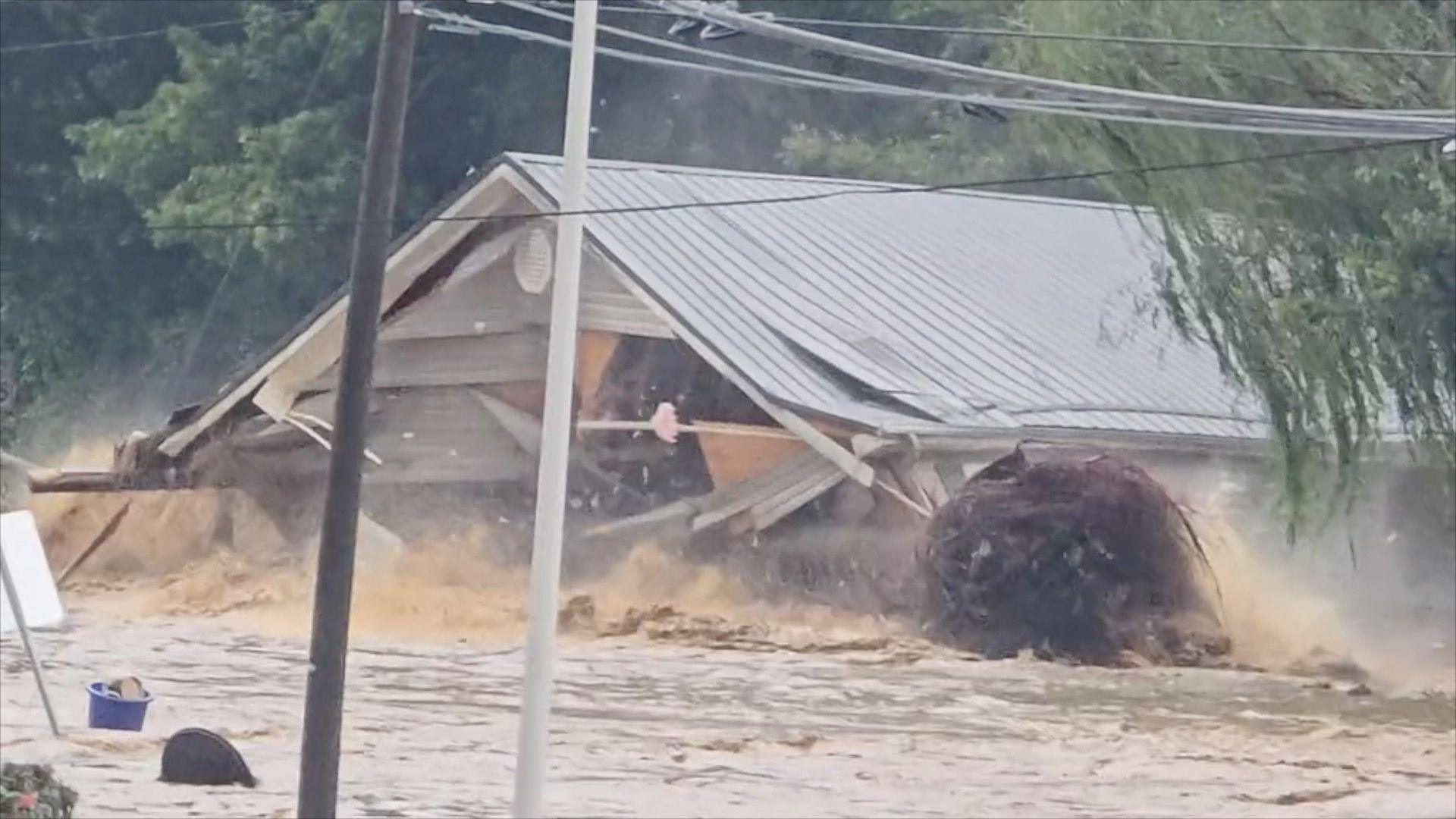 A house floats down a muddy river collapsing