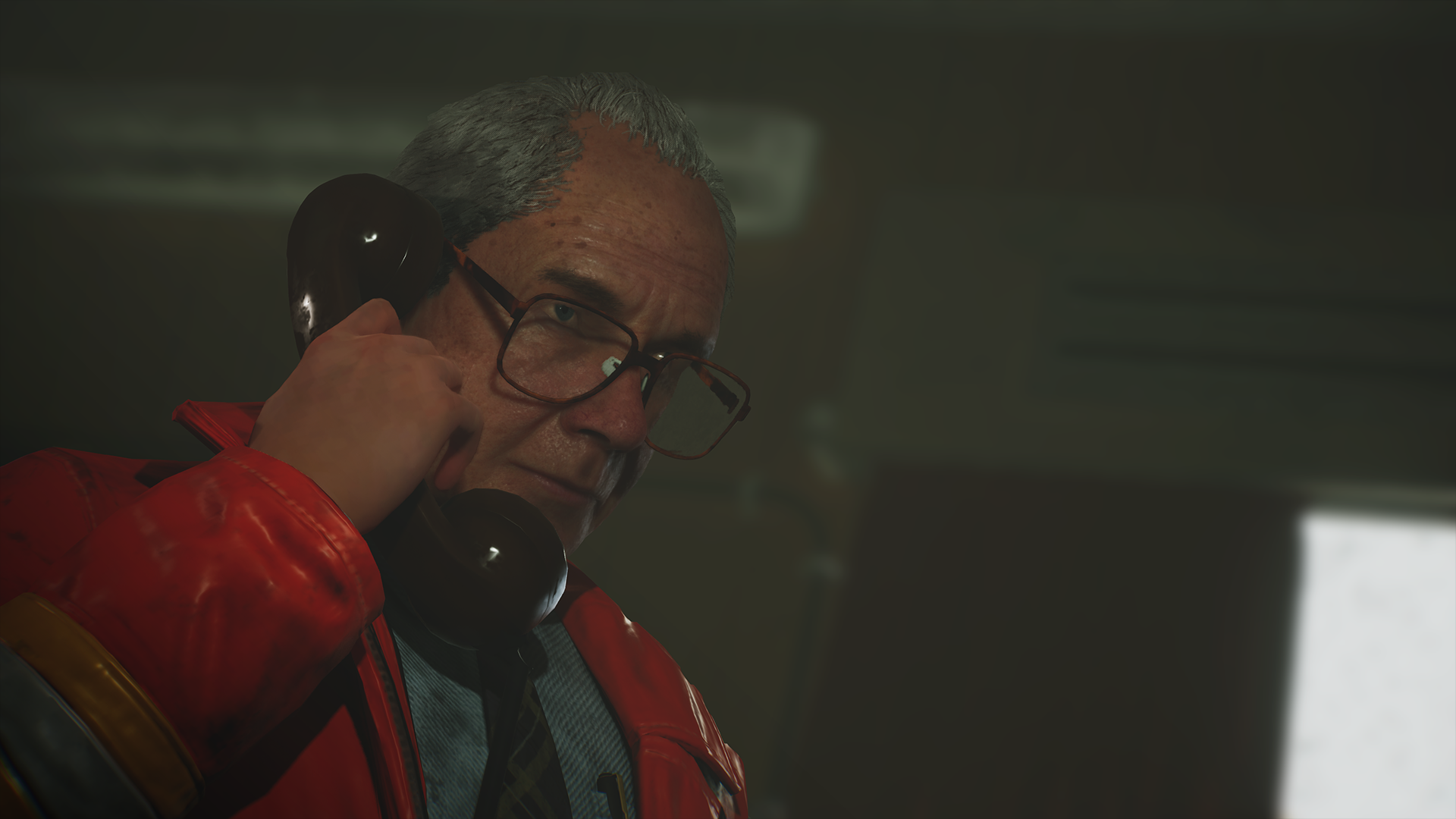 Screenshot shows a man with large glasses holding an old rotary phone handset to his ear in a dimly lit office. He wears a grave expression as he listens to the person on the other end.