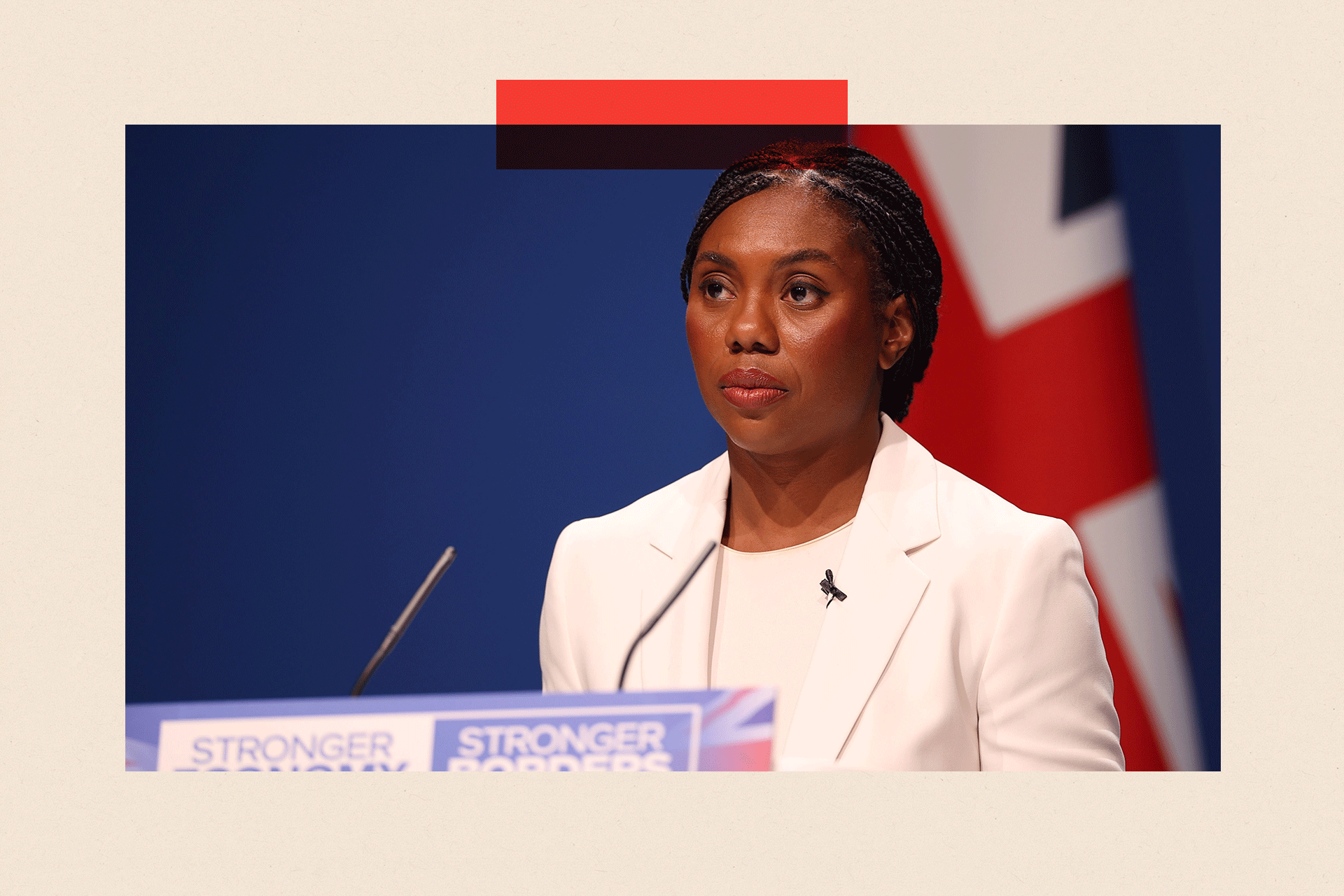 Kemi Badenoch wearing white standing by a microphone