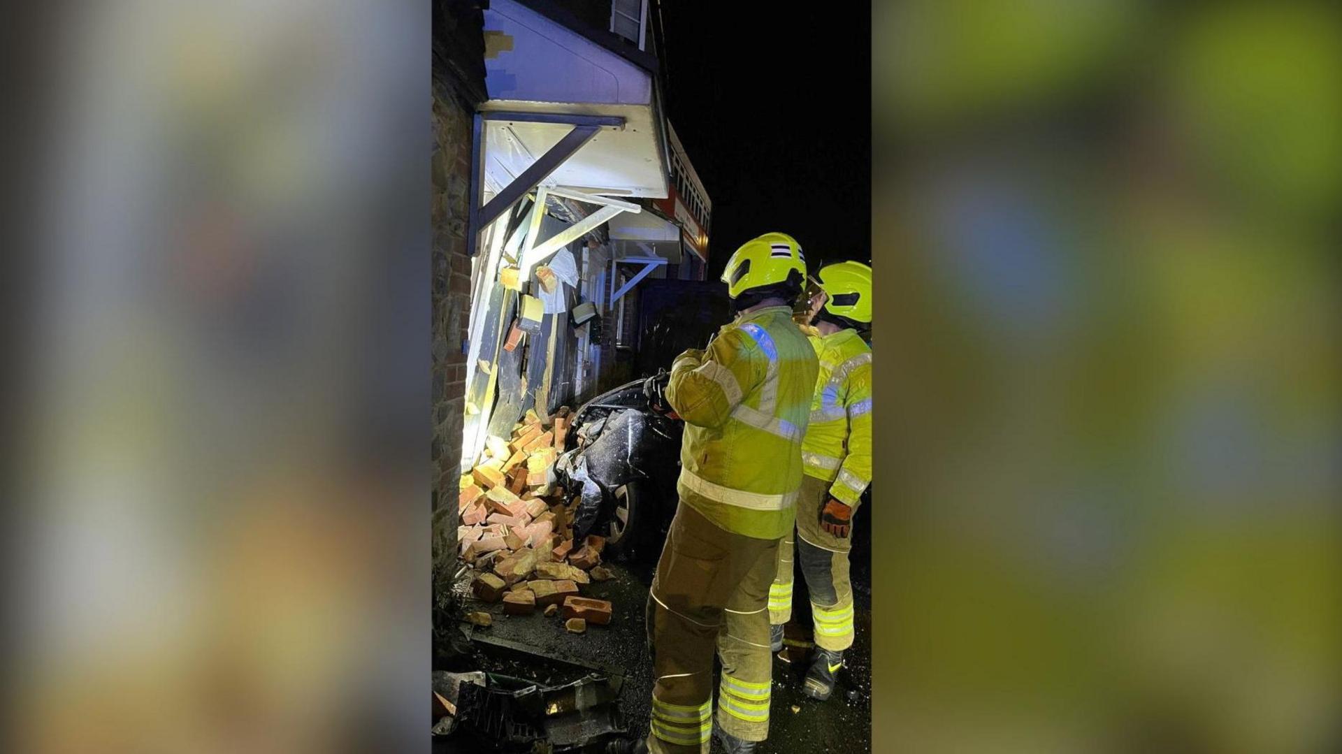 Two firefighters stand in front of a damaged house in Maidstone