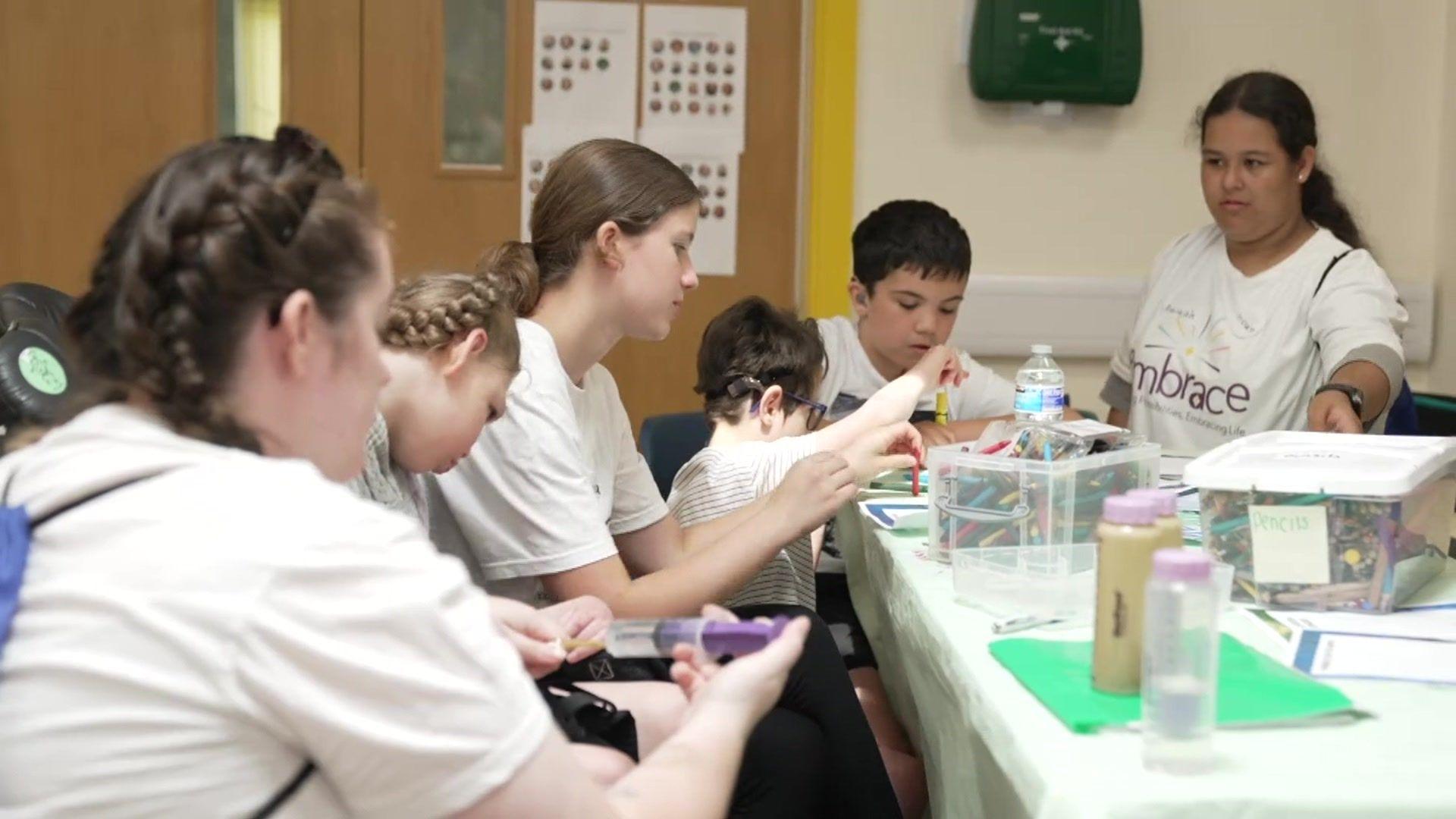 Children and adults doing arts and crafts around a table at Embrace charity