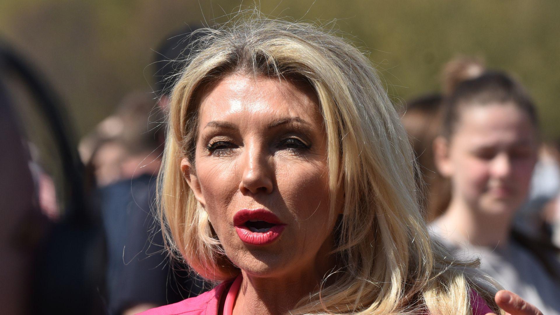 A woman with long blonde hair and a pink top