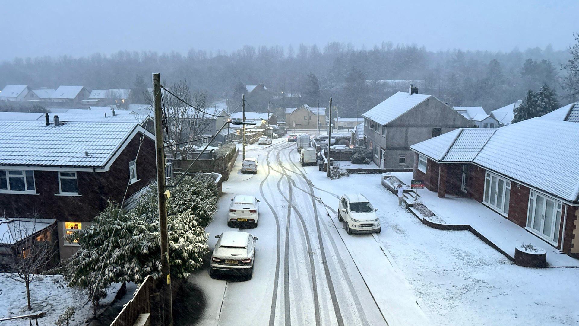 Snow on cars, houses and roads in Wales.