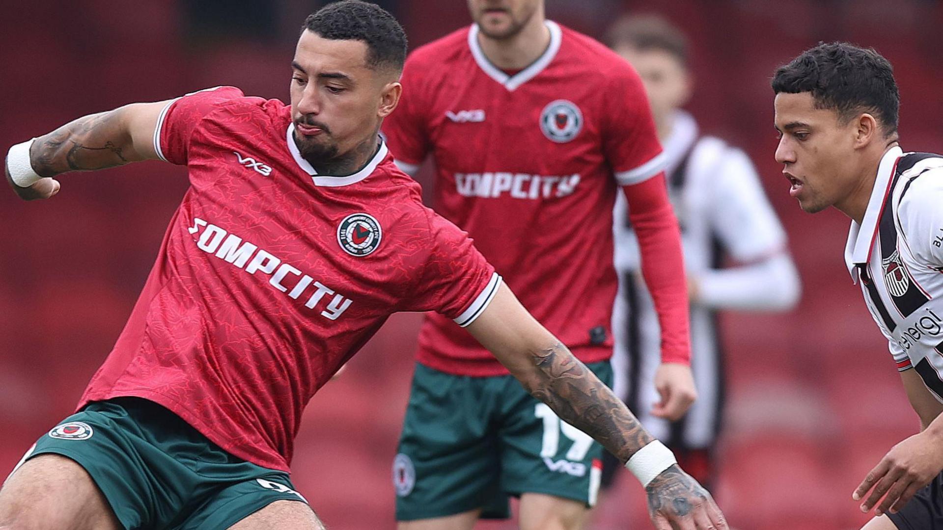 Courtney Baker-Richardson (L) of Newport and Evan Khouri of Grimsby Town compete