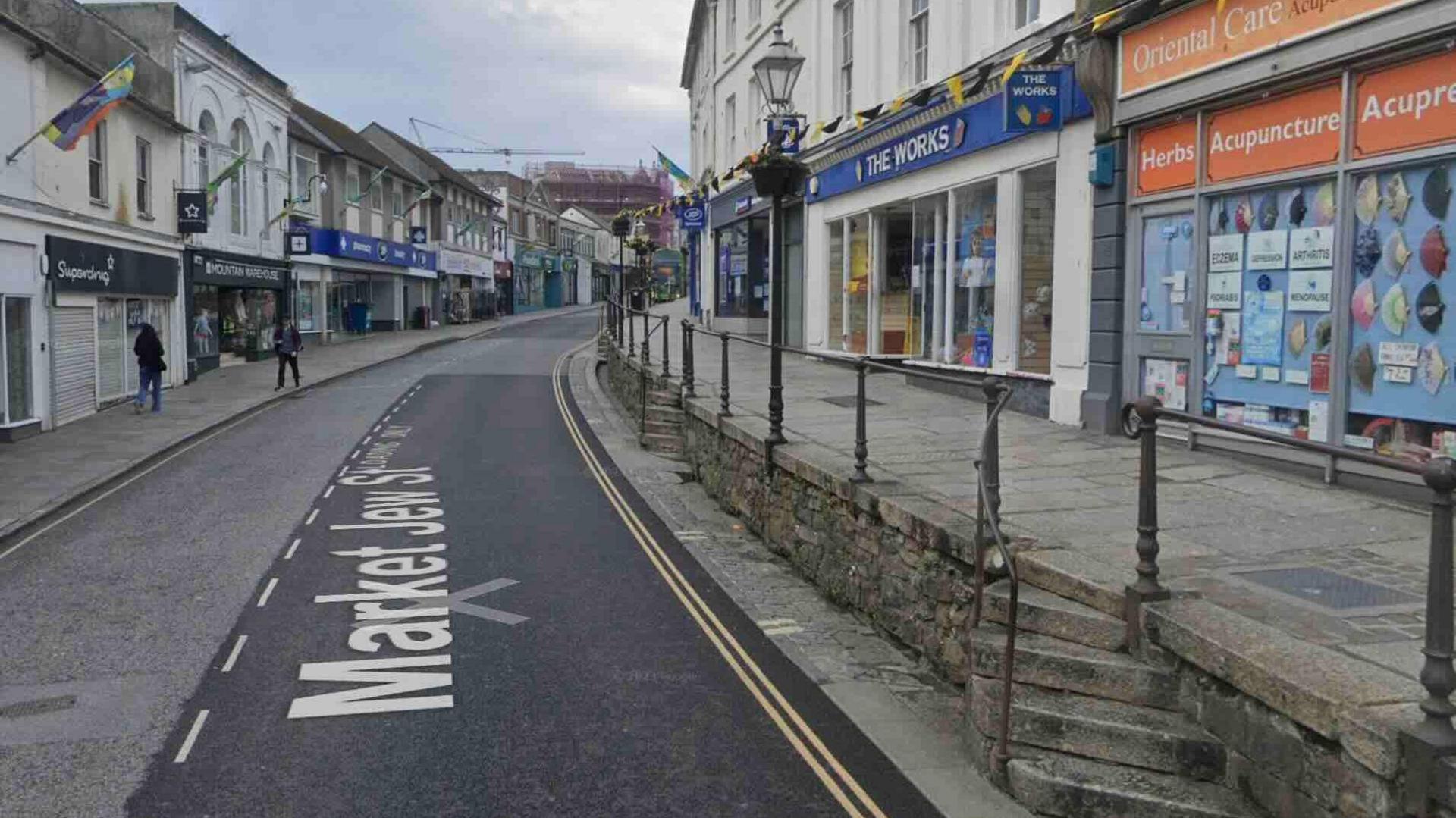 A street with shops and a pavement either side.