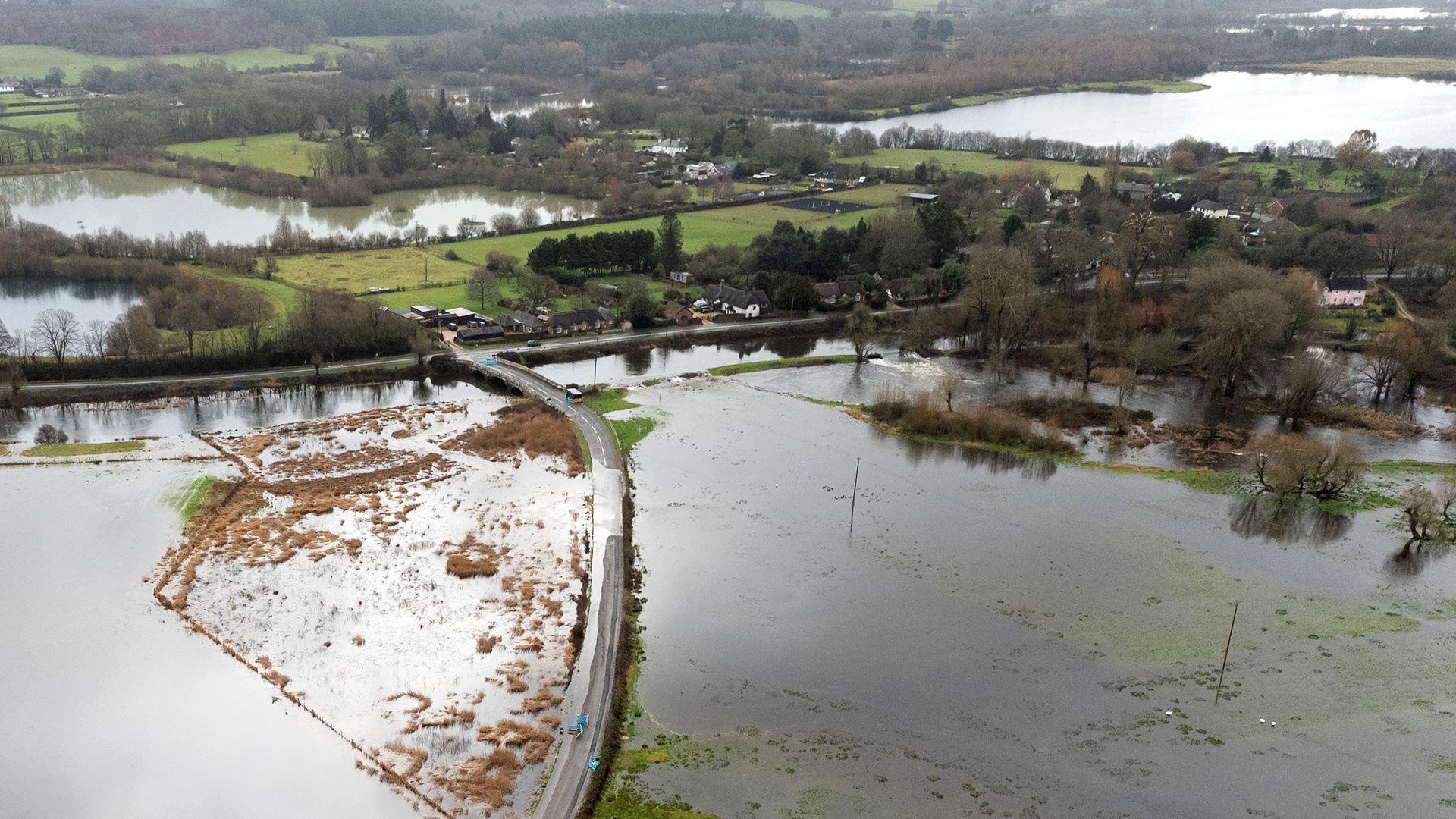 An aerial image shows a flooded road surrounded by standing water in a rural setting with trees, greenery and more floodwater in the background, in Hampshire on Friday.