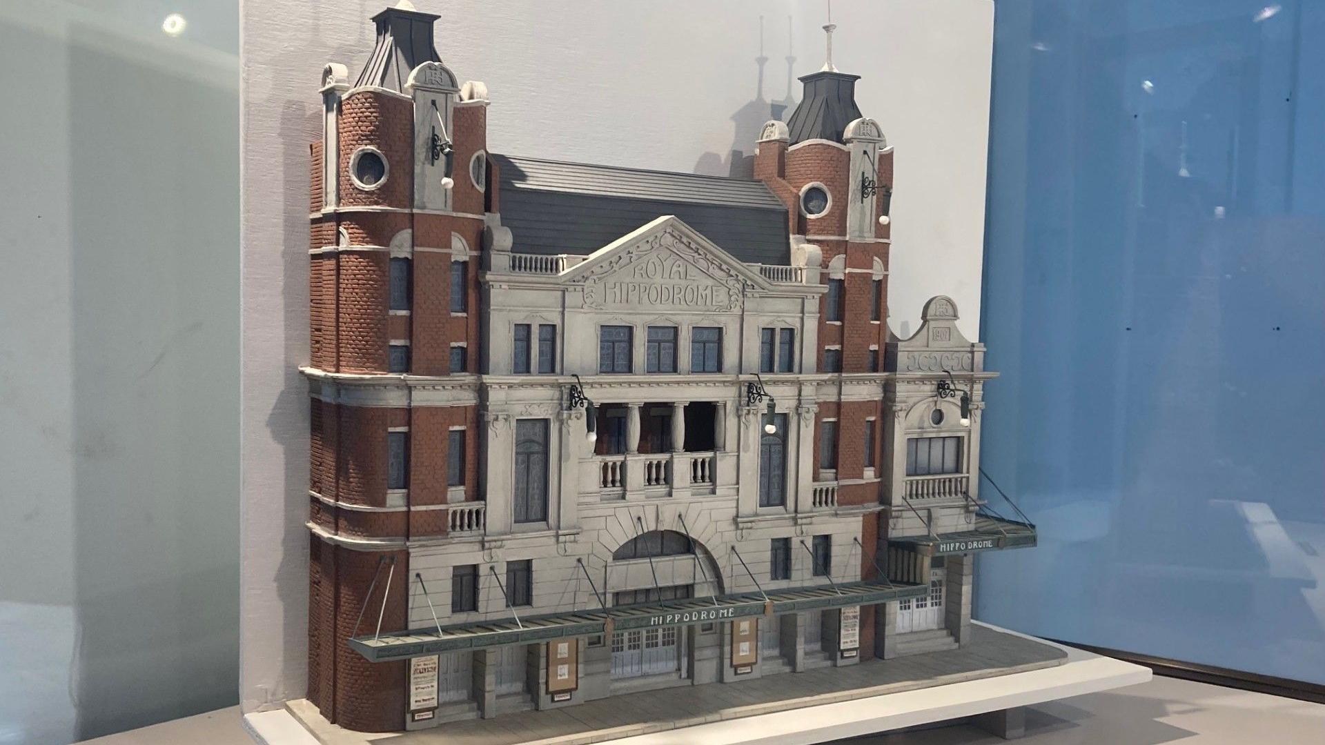 A small model of a theatre sits inside a glass display case. 