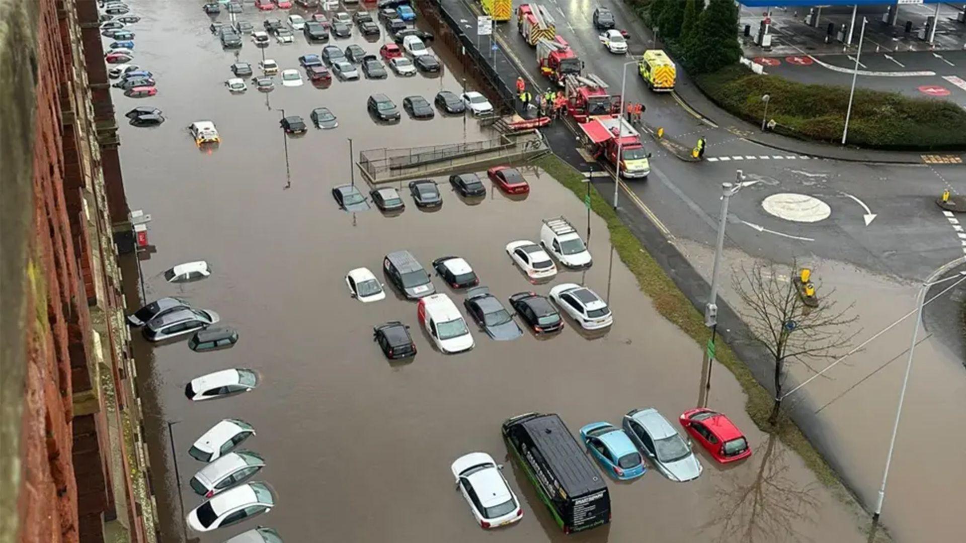 Flooding around flats in Stockport. Cars are shown from above surrounded by deep water. 