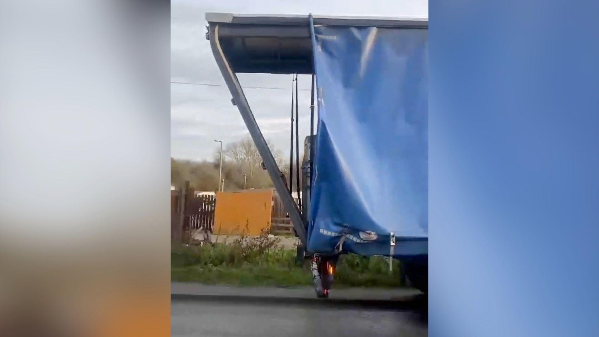 The damaged trailer frame poking out beyond the end of the vehicle at the roadside