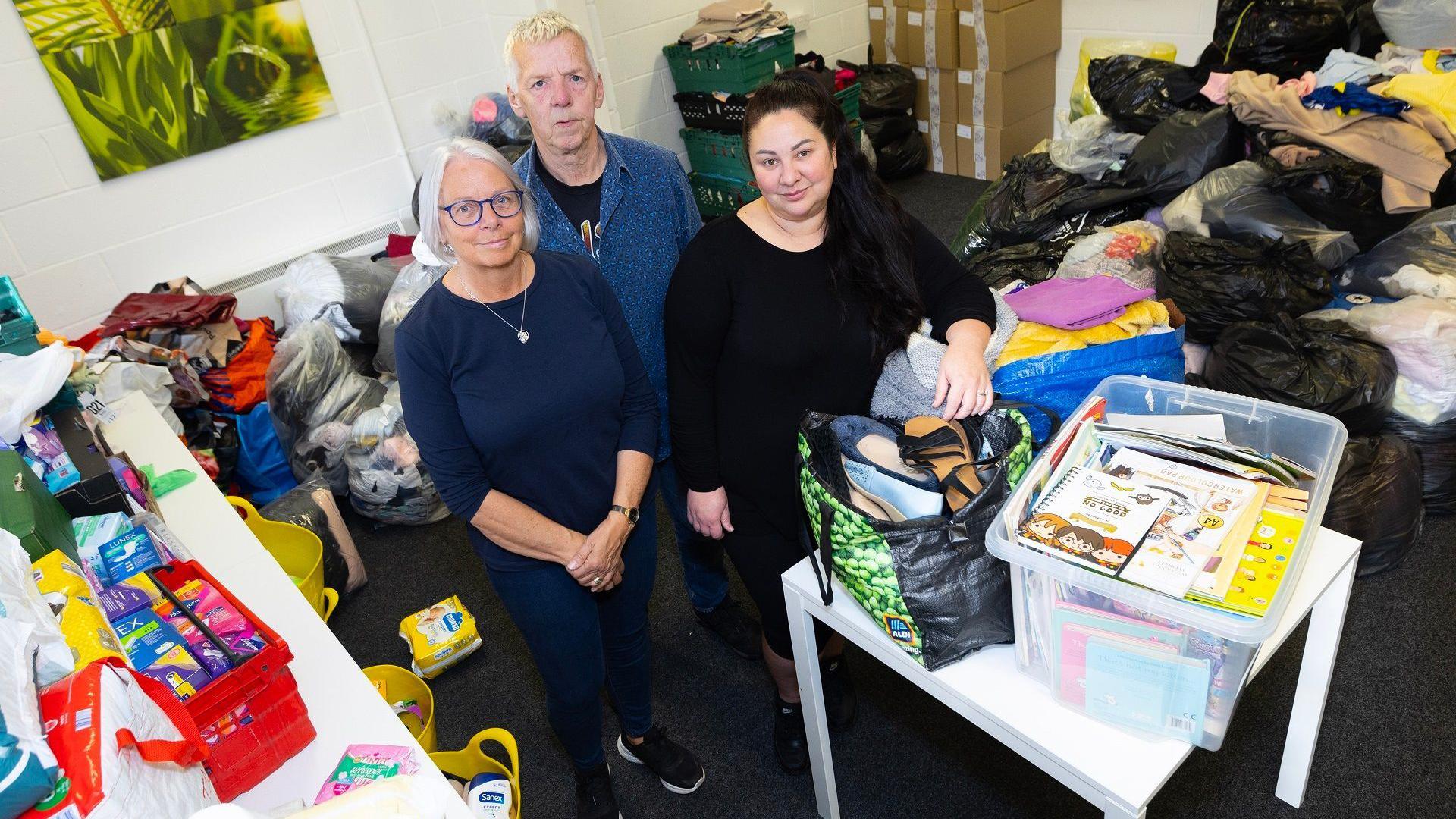 Angela Charlton, Michael Taylor and operations manager Amy Sturdy, stand together among some of the many donations which are in boxes and bags.