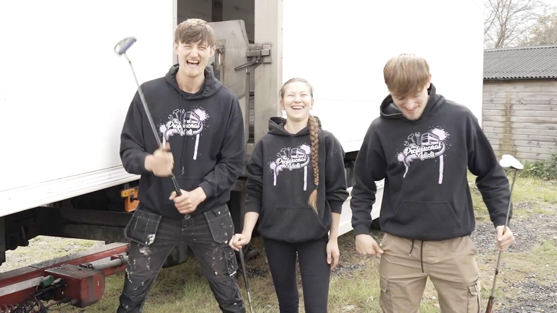 Three young people who built the lorry laughing infront of it in work clothes