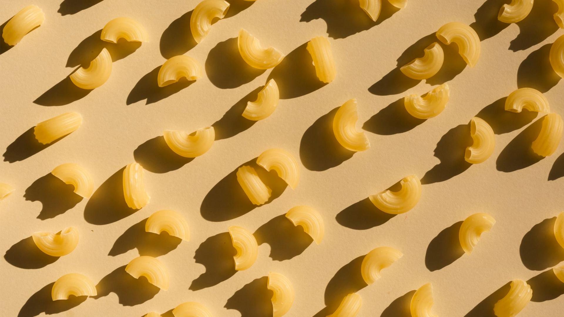 Dry pasta on a beige background with shadows