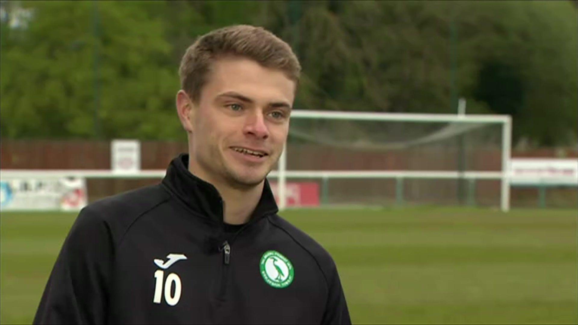 JJ Lacey standing on the pitch and smiling