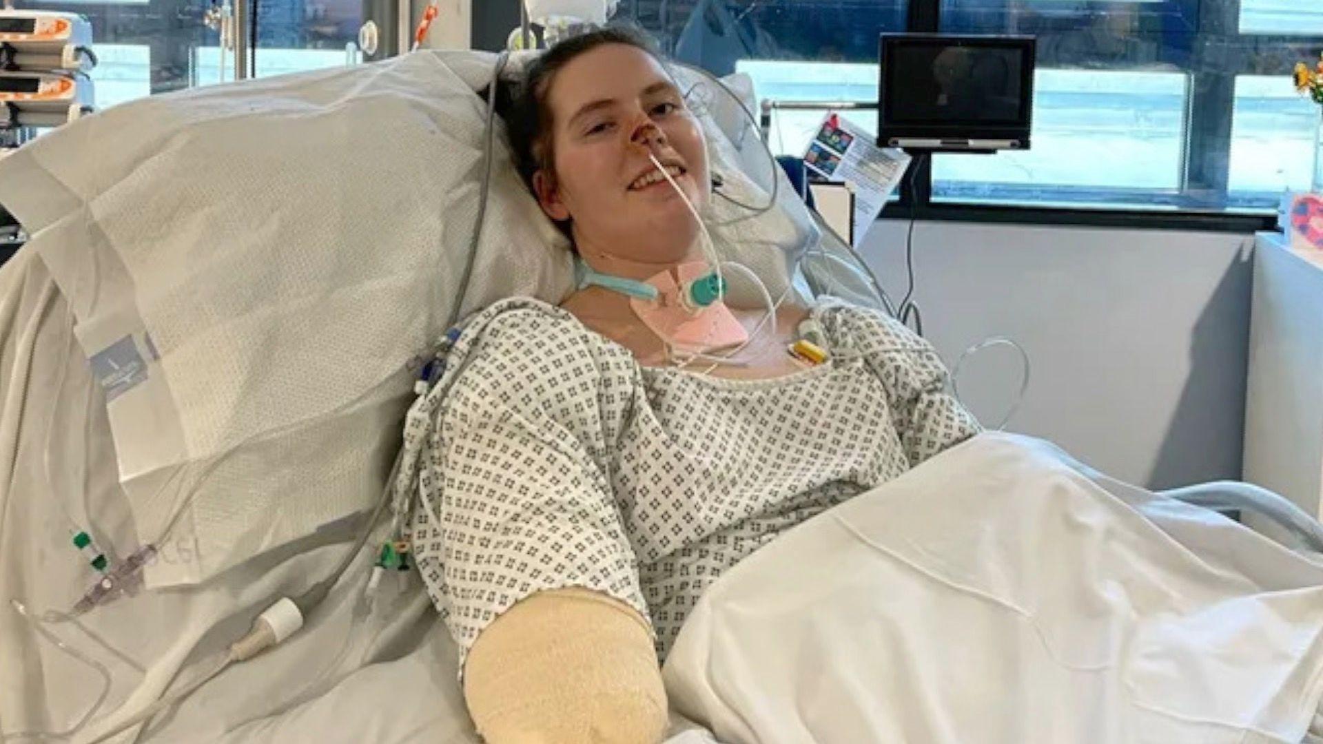 Lily lies on her hospital bed having had her limbs amputated but she smiles at the camera