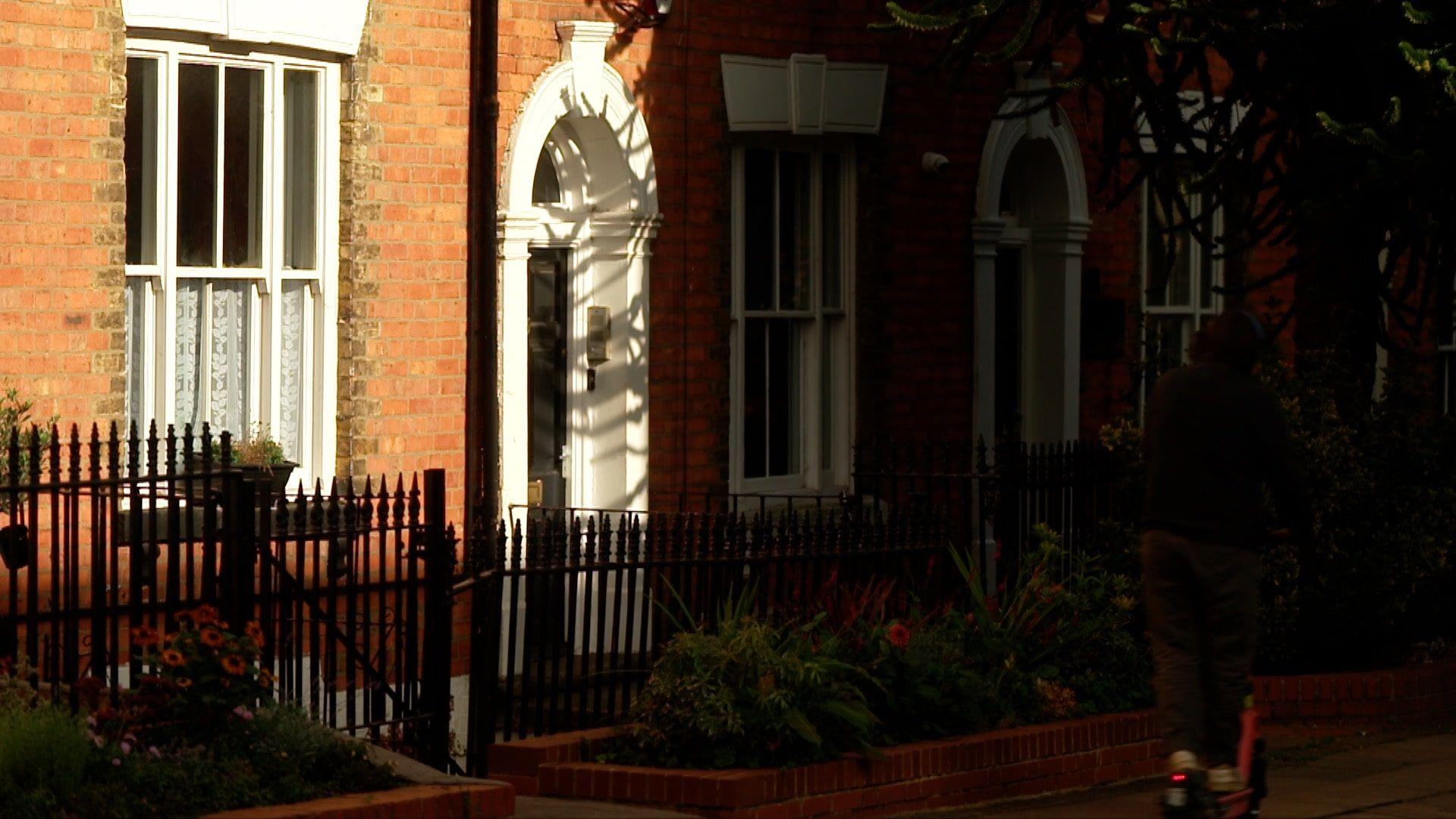 The front entrance of a Northampton townhouse, with white cornicing on the windows and archway of the door. Half the image is in the sun's shadow.