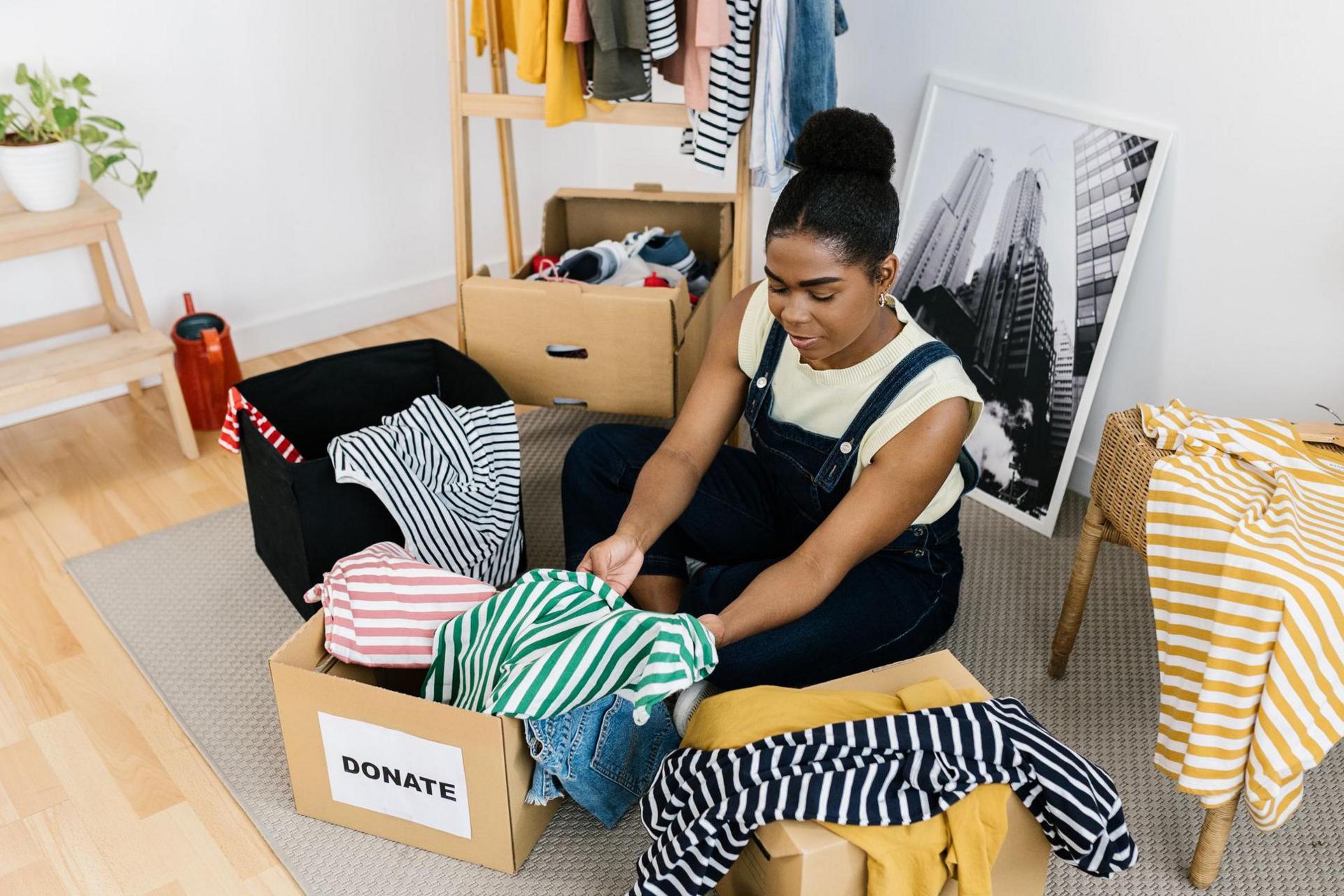 A black woman organising clothes into a donations box