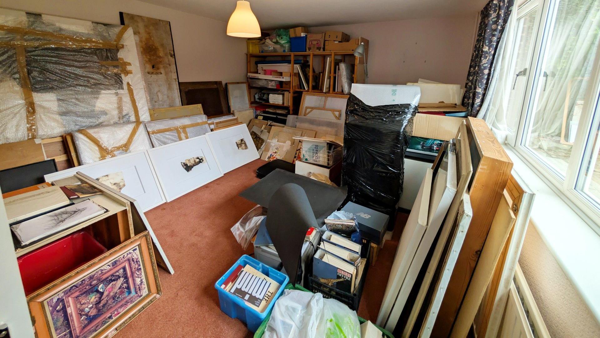 A medium sized suburban room, partially filled with frames and works of art