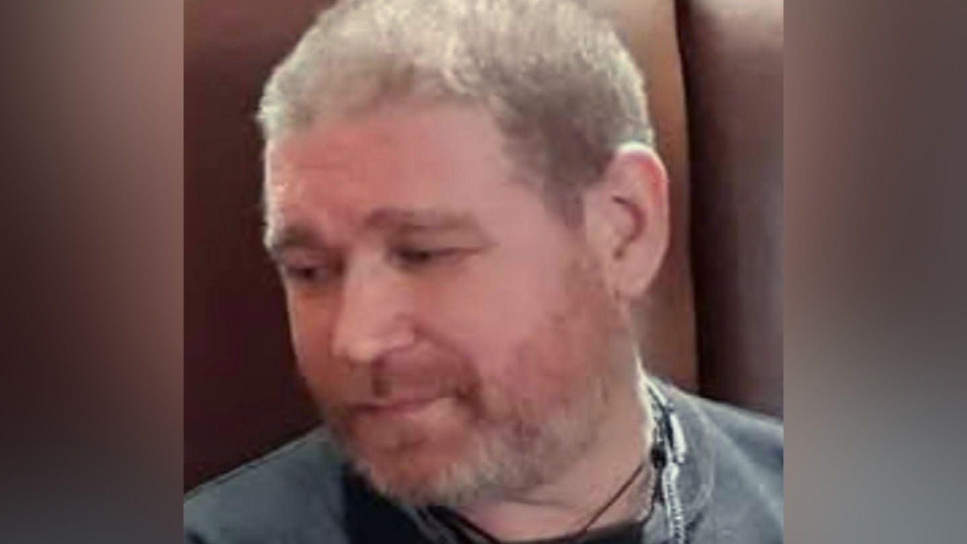 Richard Sanders wearing a black T-shirt. He is looking down to his left, towards the ground