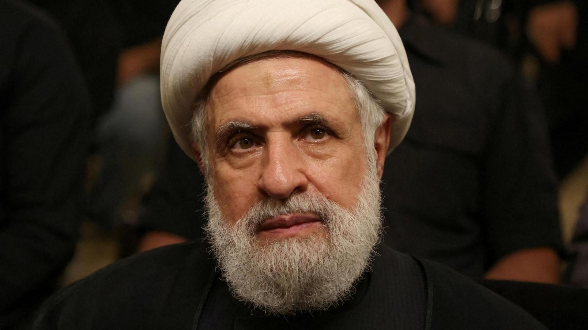 Qassem, a bearded man, looks past the camera to the right