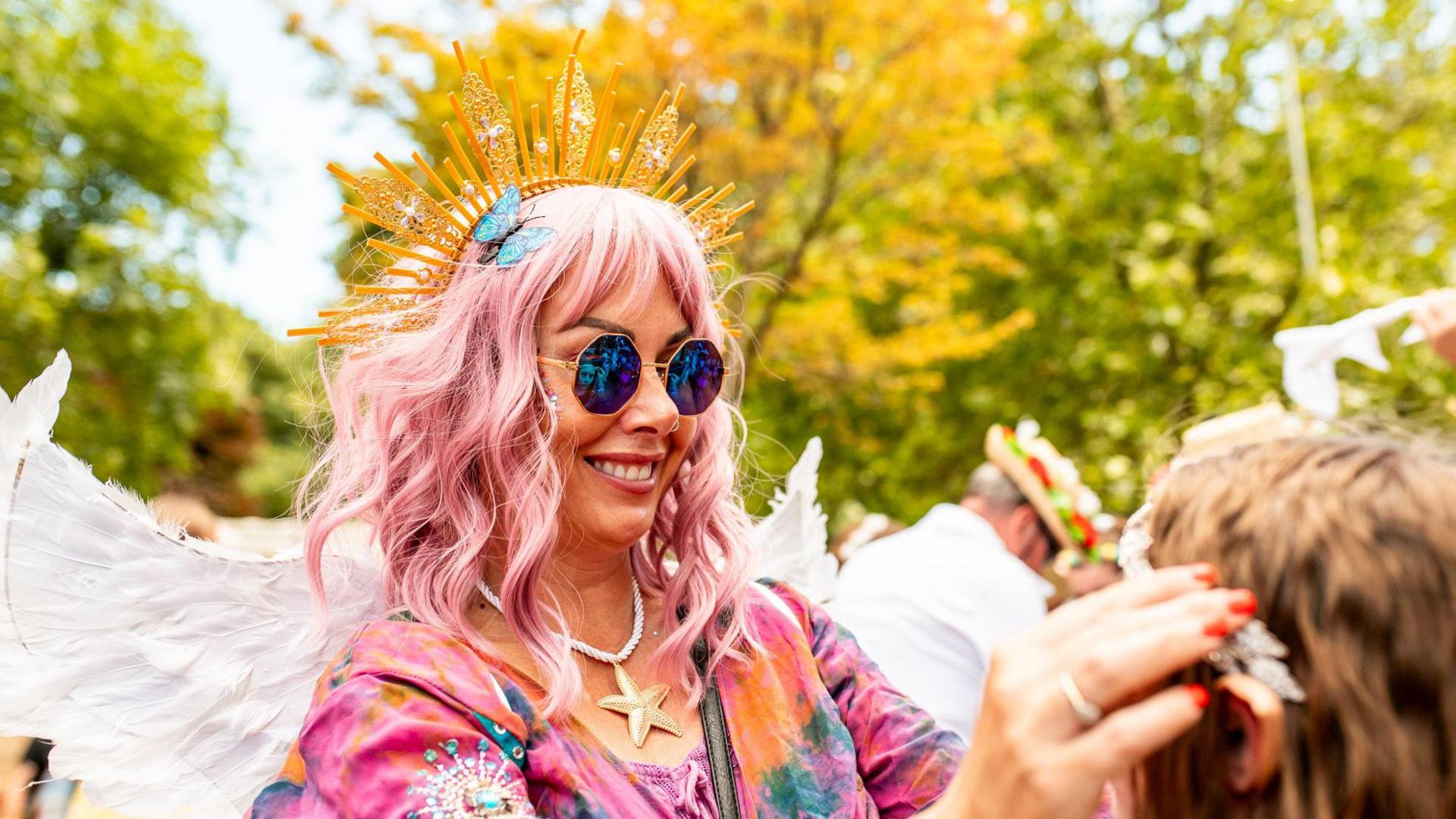 A woman in sunglasses moving another girls tiara around her head