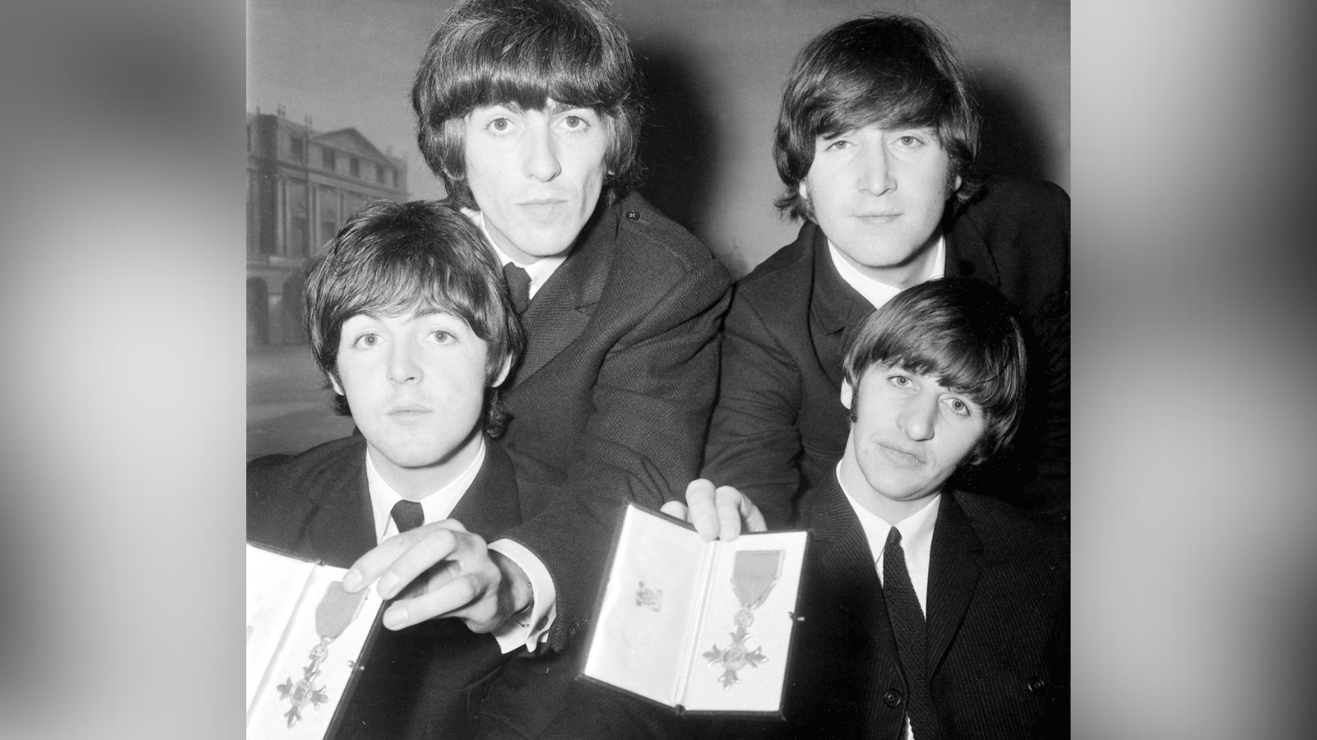 A black and white photo of four men, in suits, holding medals.