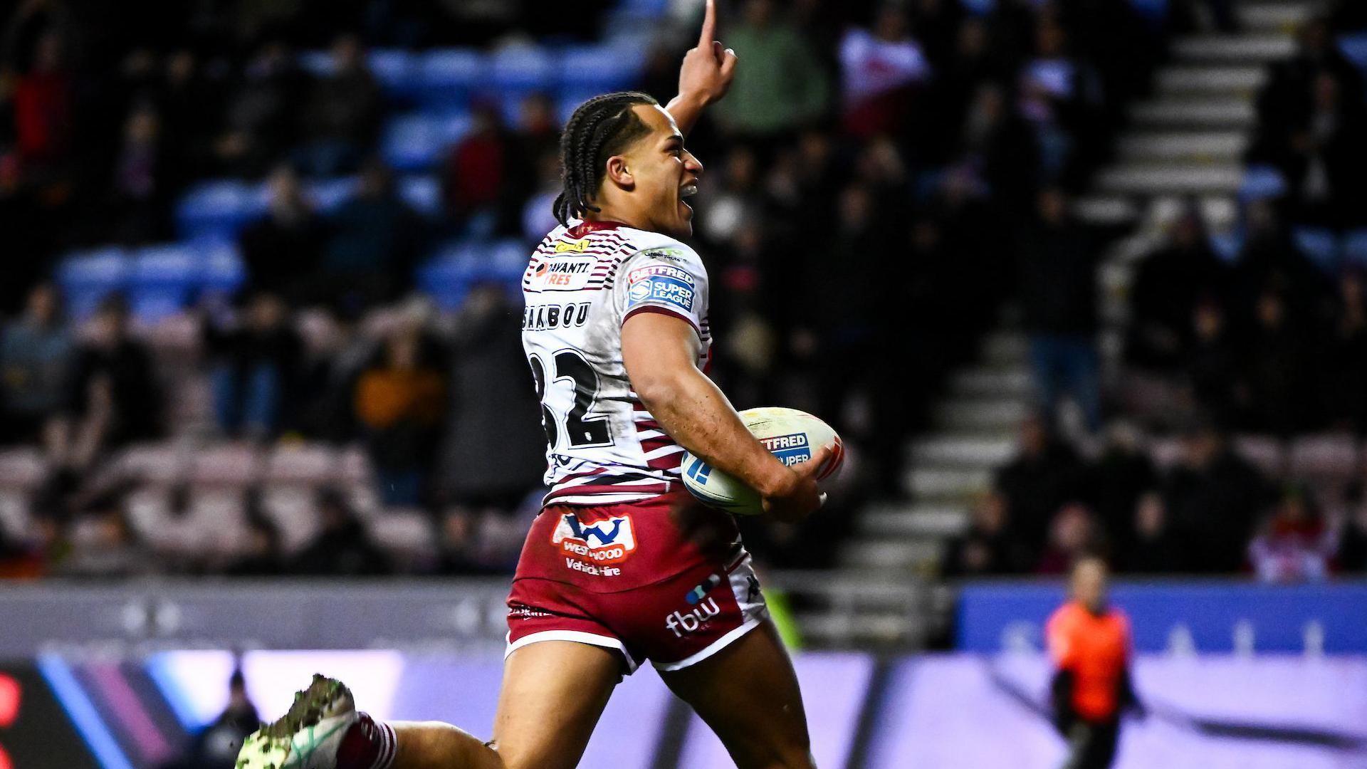 Dayon Sambou points his left hand in the air to celebrate scoring on his Wigan debut.