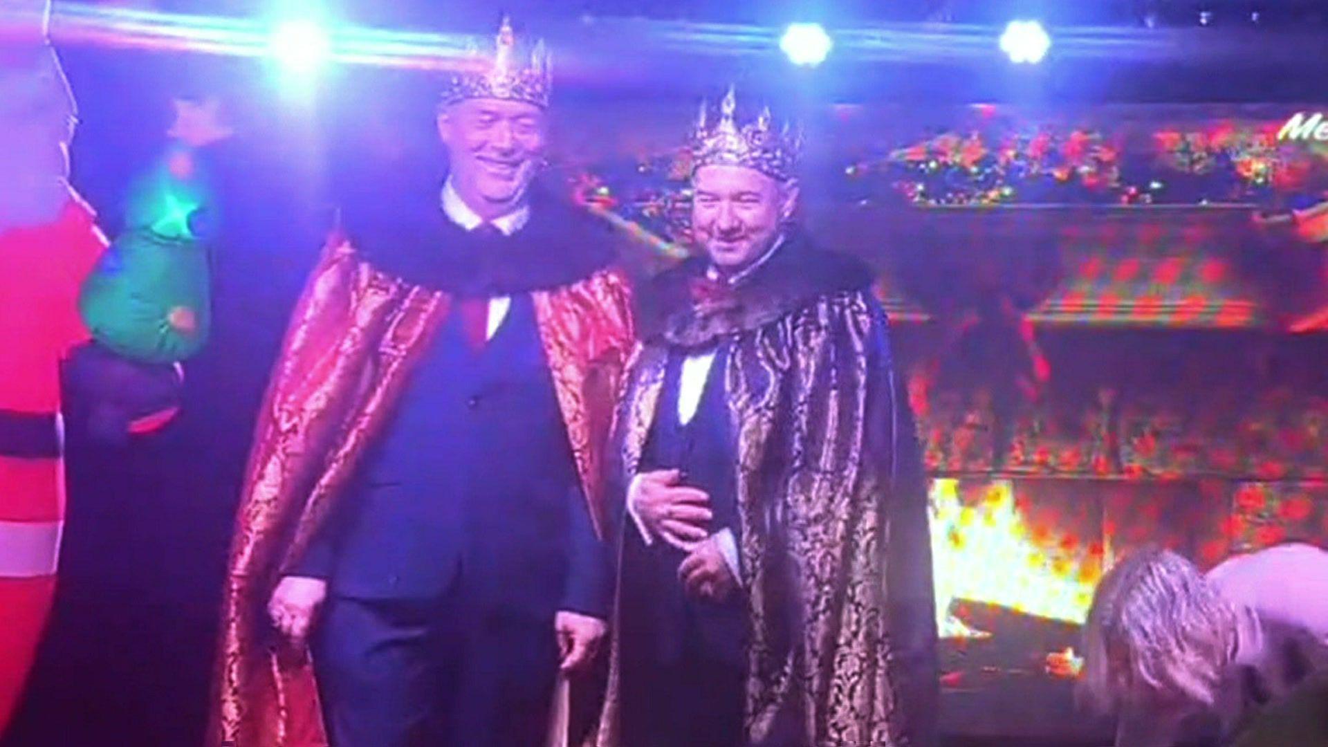 Paul and Jason wearing suits, capes and crowns. They are stood side by side and are both smiling. 