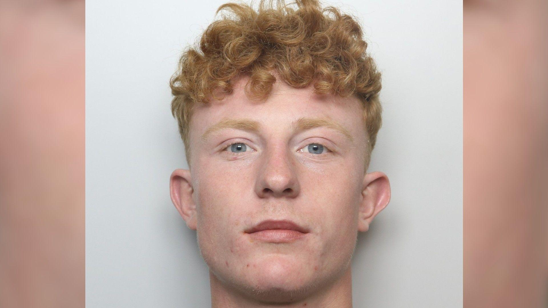 A police mug shot of Josef Poutch. He has curly ginger hair and pale blue eyes.