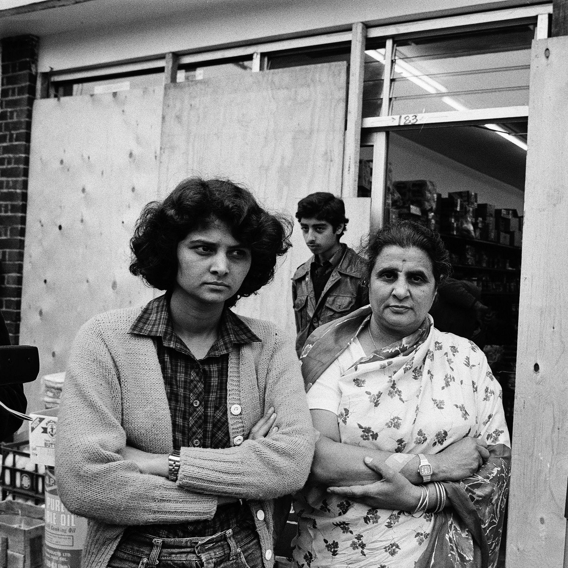 People gather outside a shop with boarded up windows on The Broadway in Southall following rioting, picture date 4 July 1981