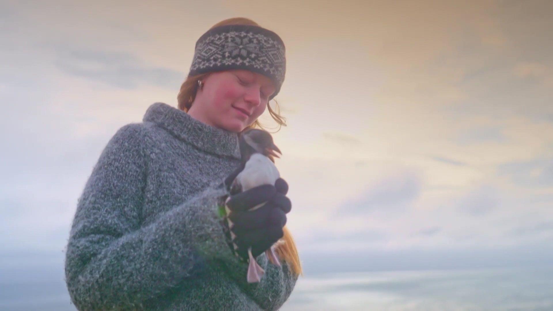 Girl holding baby puffin. 
