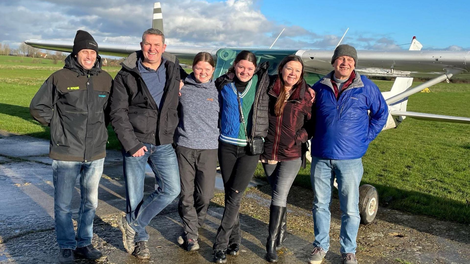 A group of people, including 16-year-old pilot Holly Rowley-White, standing in front of an airplane