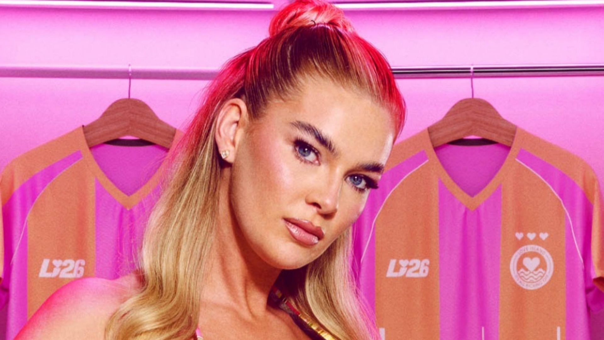 Robyn Langton, who is wearing a bikini, is standing in a changing room surrounded by pink and orange football shirts
