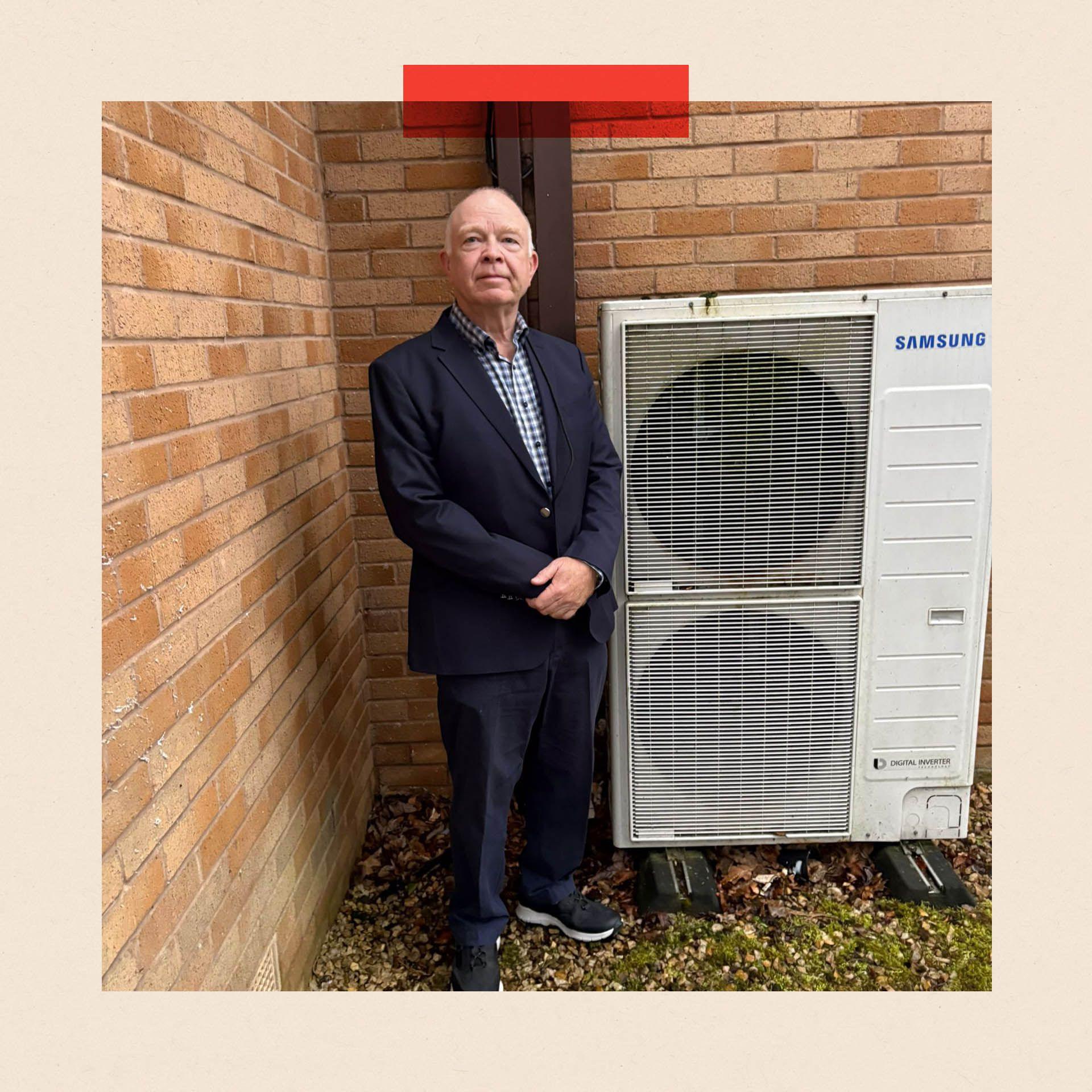 Gavin Tait stands next to his heat pump