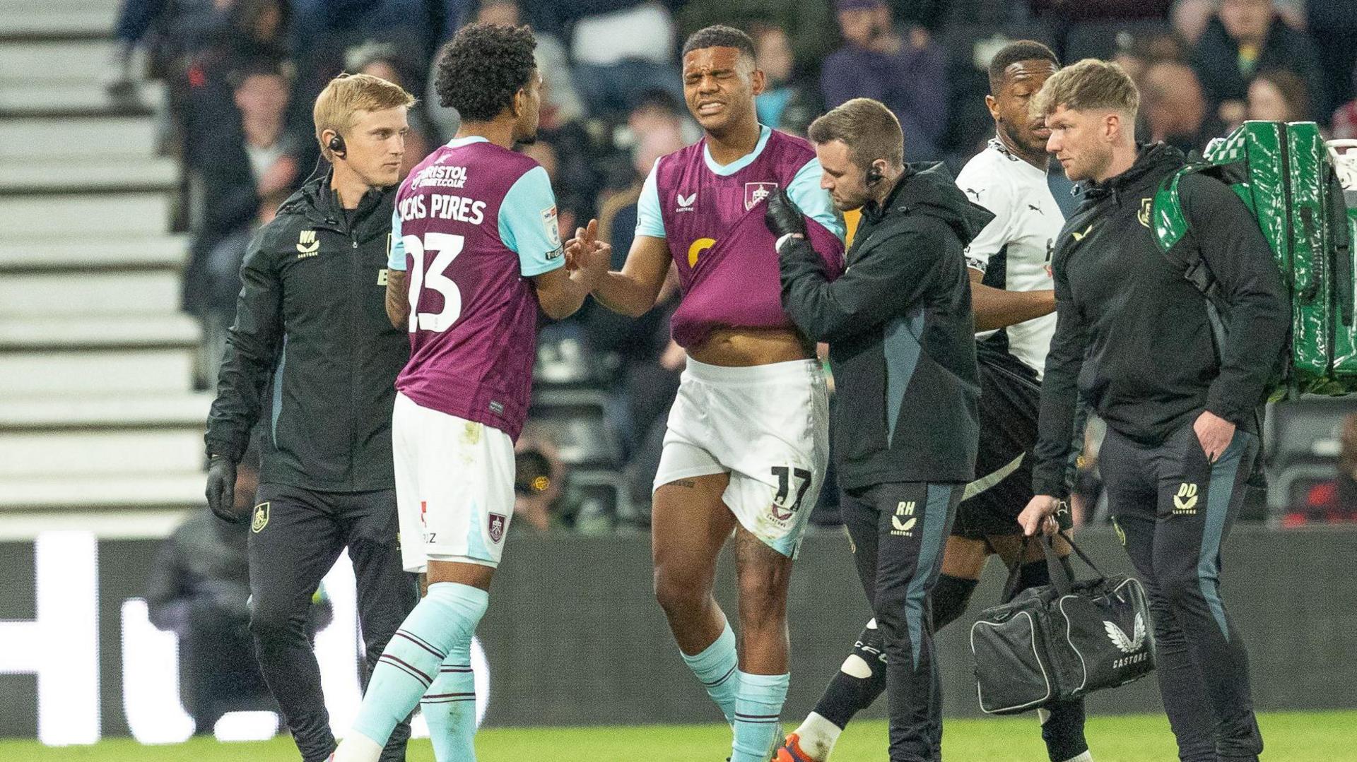 Burnley's Lyle Foster is helped from the field after injuring his shoulder against Derby