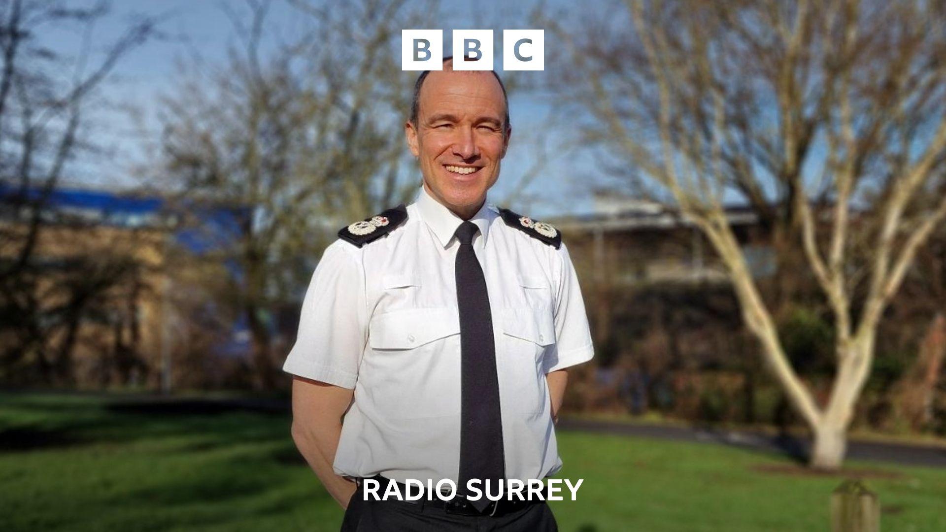 Surrey police chief constable Tim de Meyer, with hands behind back, smiling in front of the camera in uniform