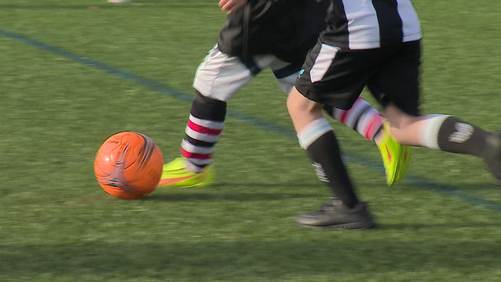 Close up of the legs and feet of two youngsters chasing a football