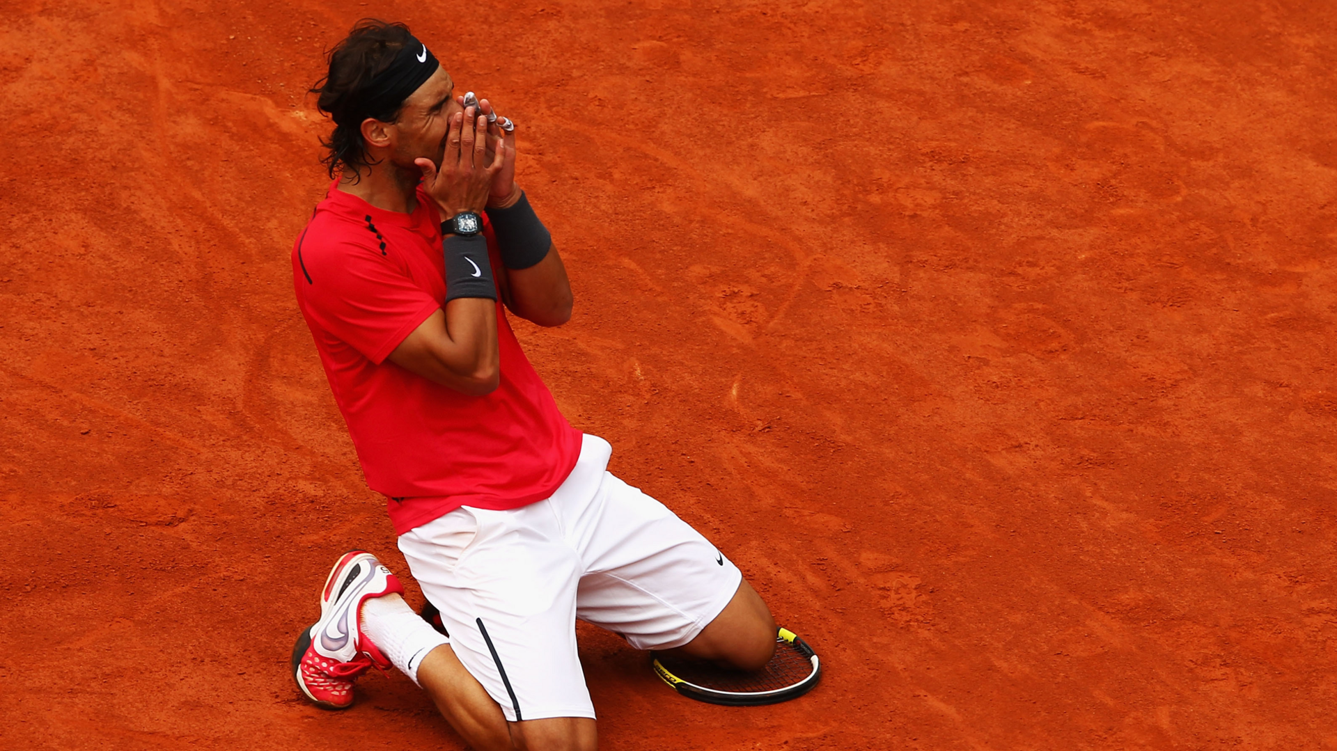 Rafael Nadal celebrates on his knees on the clay court