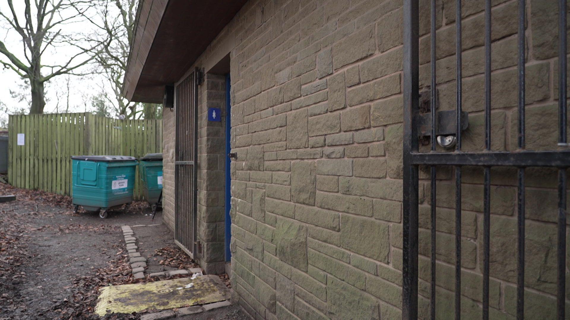 A brick building with two entrances with a toilet sign