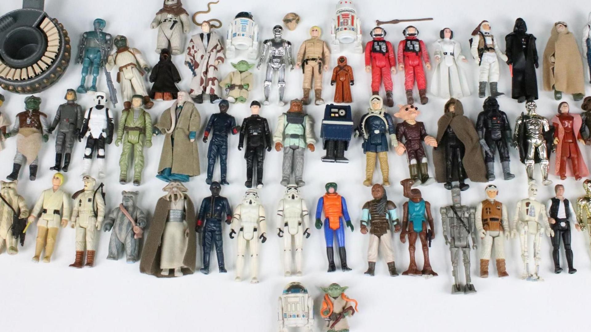 Dozens of Star Wars figures laid on a white table