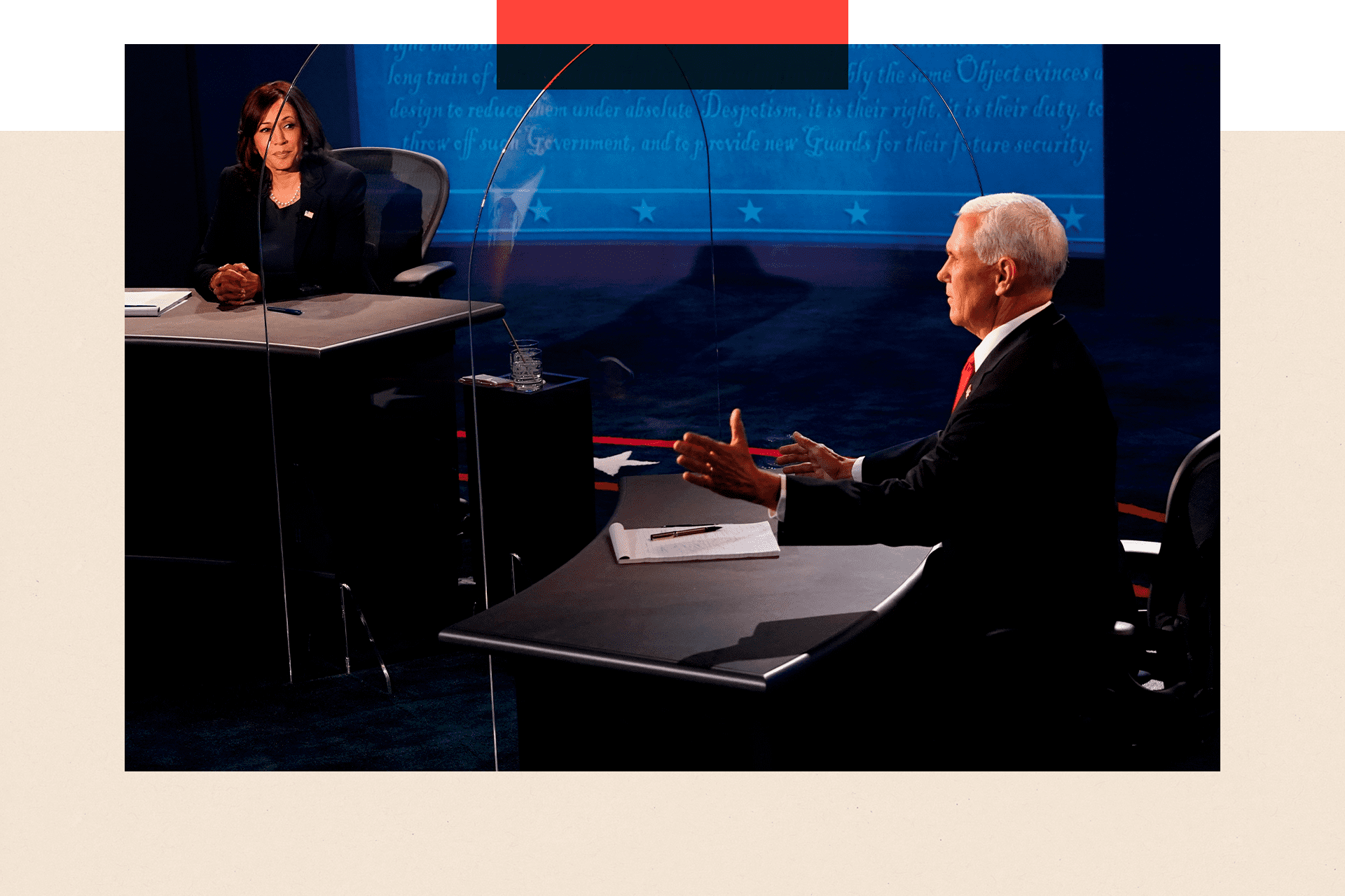 Kamala Harris in a dark suit with her hands clasped sat at a desk while at a desk to the right of the picture Mike Pence, wearing a blue suit and red tie, gestures with his hands