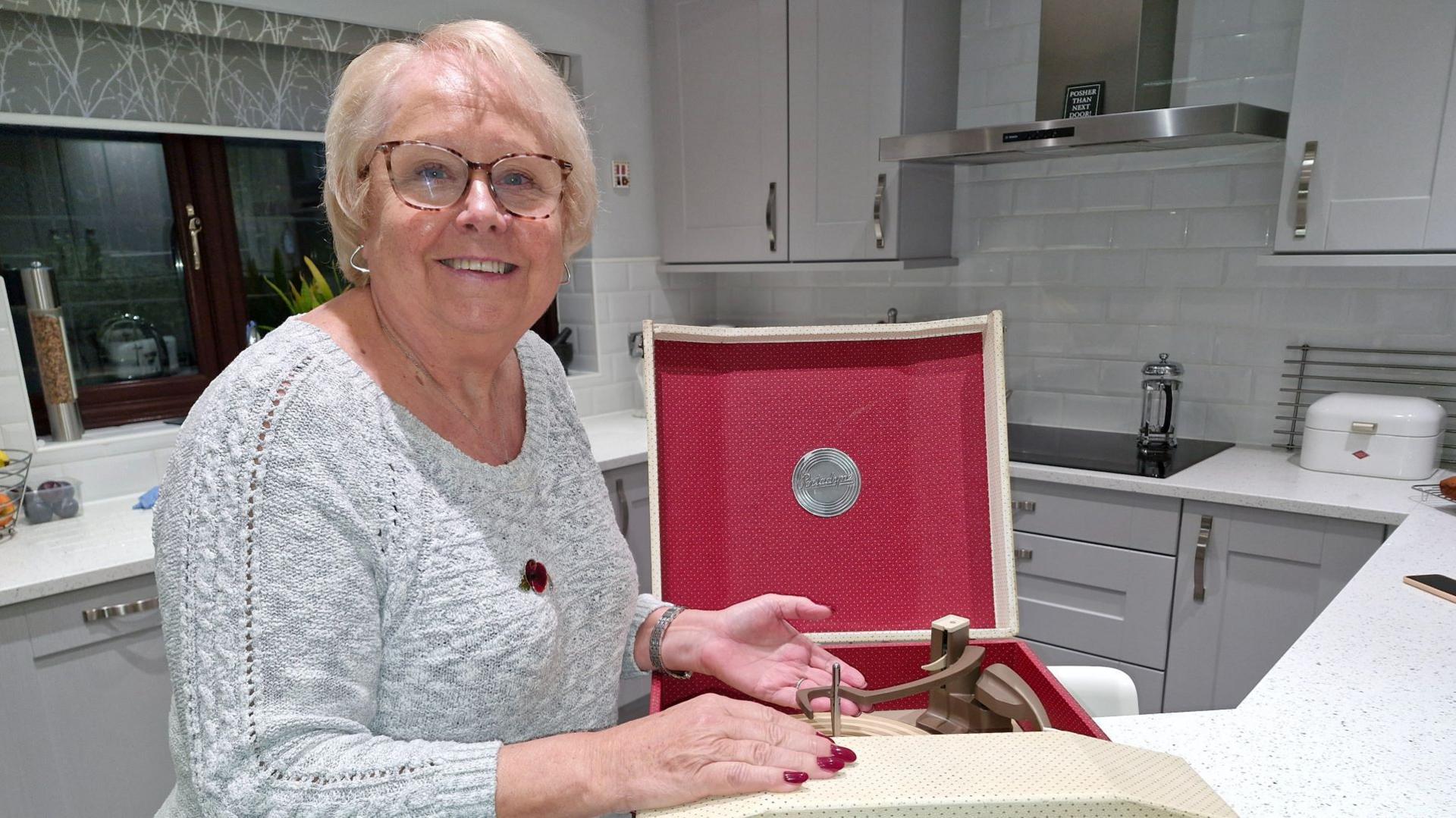 Smiling Ellen Hammond stands next to her vintage record player