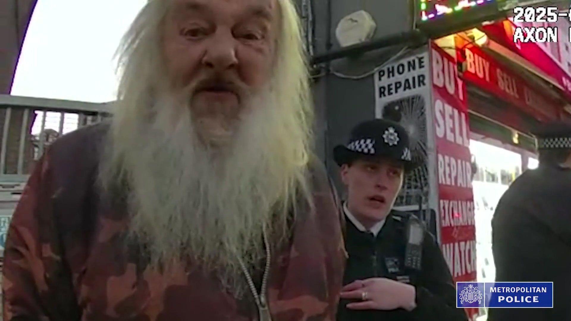 Met Police bodycam footage shows David Cheneler being arrested in front of a phone repair shop in the street. A female police officer stands beside him.  
