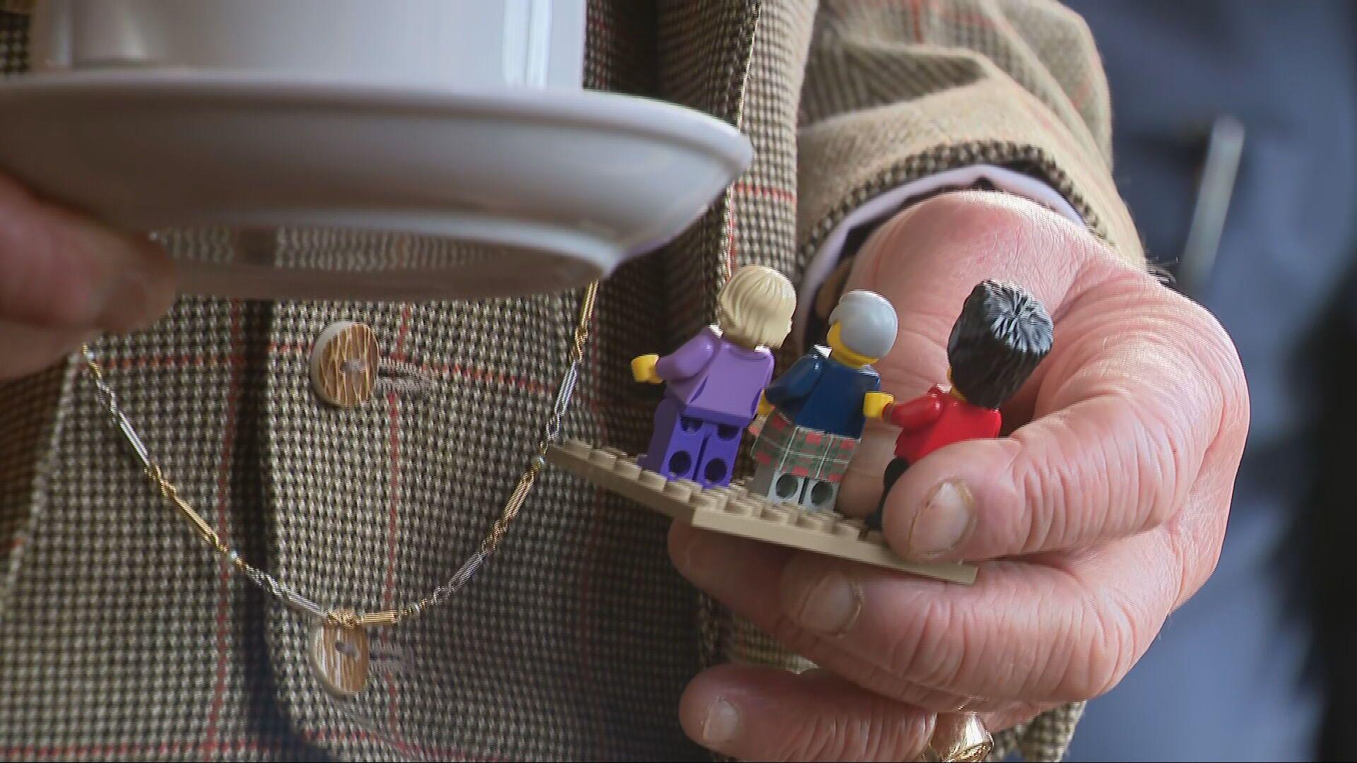 A close up of King Charles holding Lego minifigures of the King and Queen, with a Scots Guard, built by Ballater Lego Club to mark the 150th anniversary of the Albert Hall.