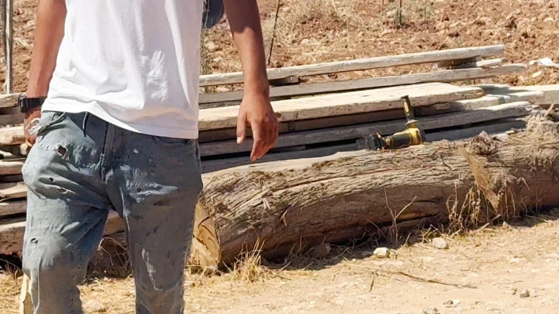 Screengrab from a video showing an angle-grinder or similar power tool lying on a log behind an Israeli settler during a settler attack on a Palestinian home in the village of al-Mughayyir, near Ramallah, in the Israeli-occupied West Bank (11 July 2026)