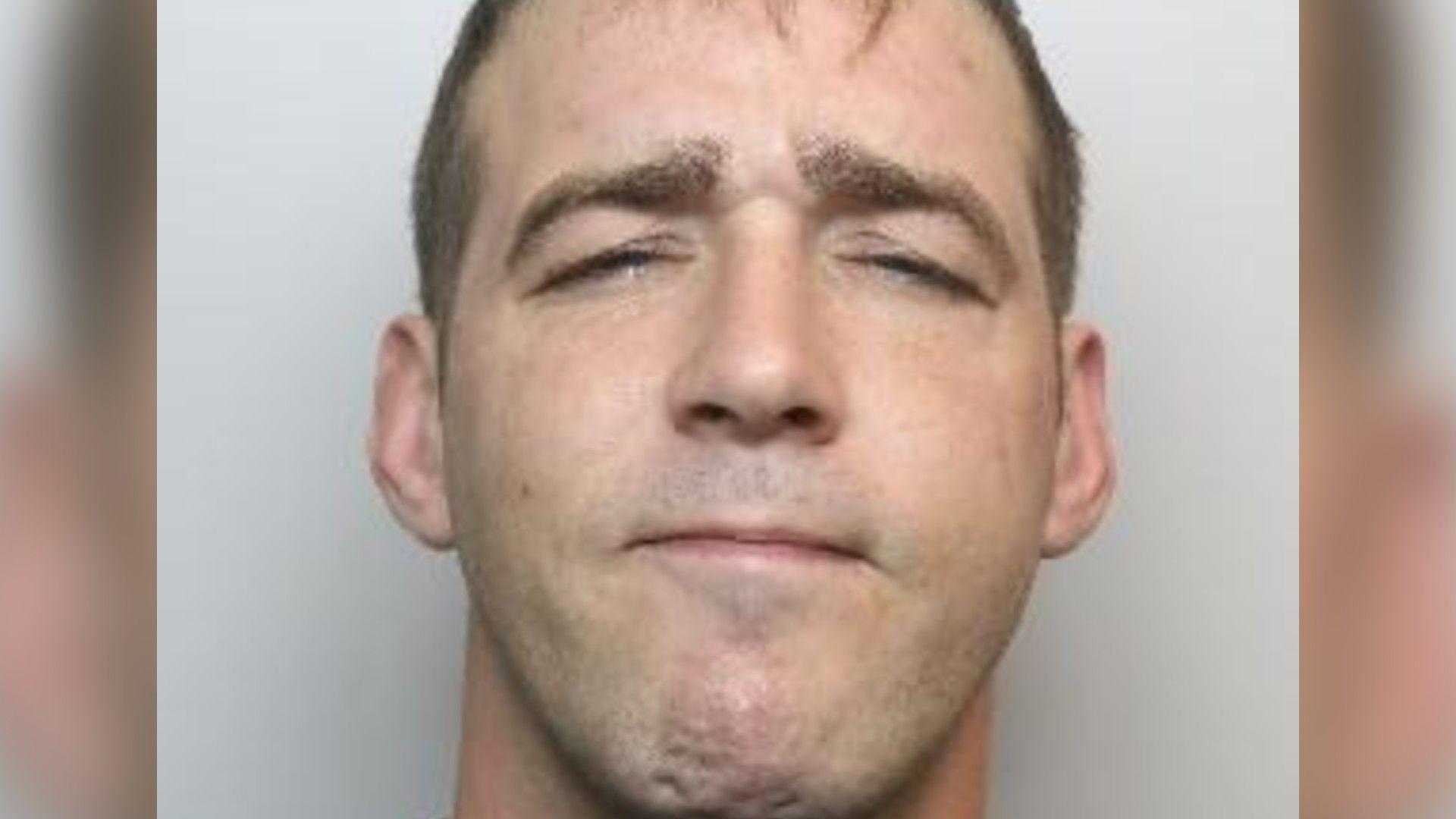 A police mugshot of Michael Stewart. He has short, dark hair.