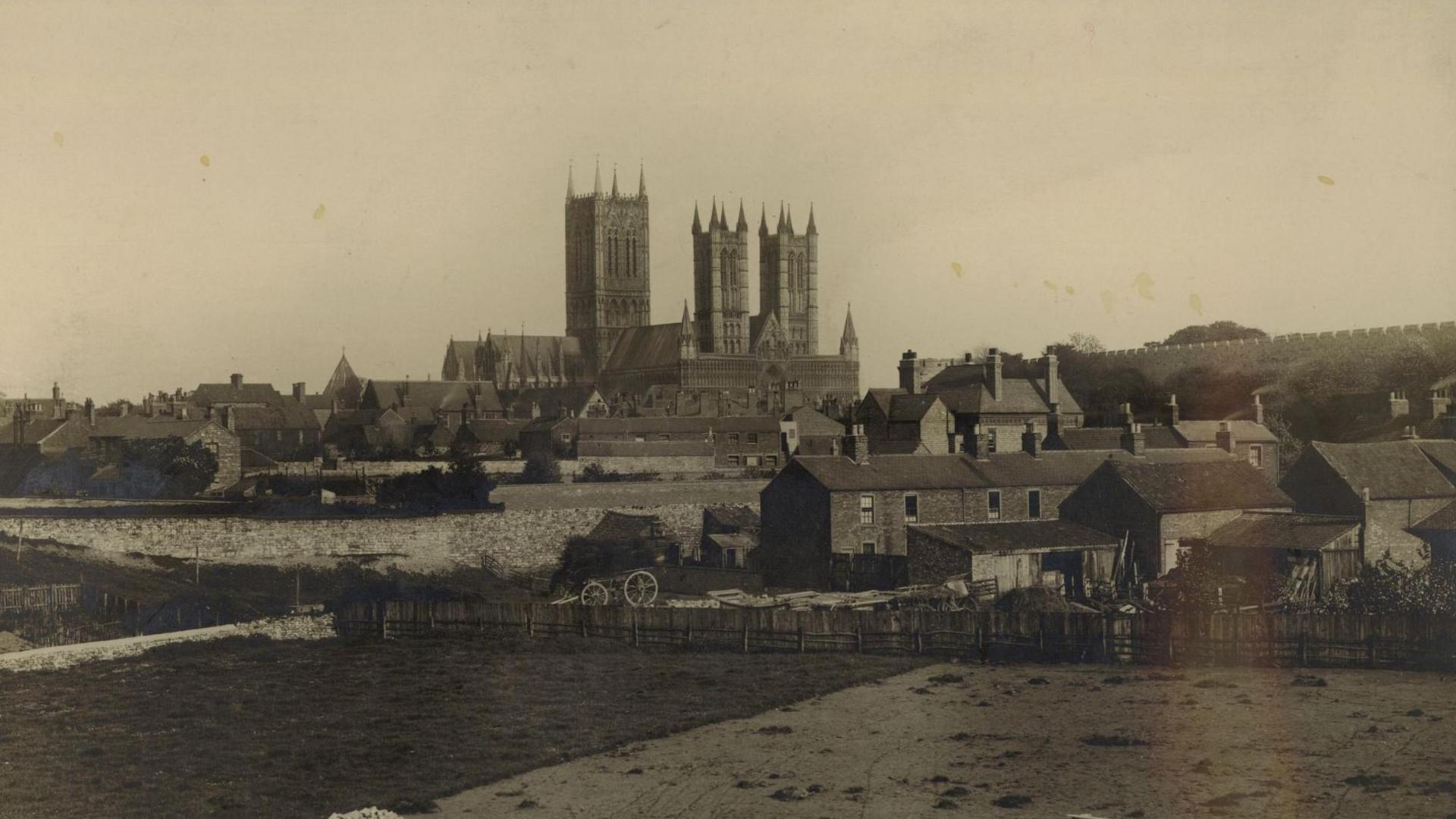 An archive photo of Lincoln Cathedral in 1904 at the top of the city,
surrounded by rural buildings, walls and cottages.