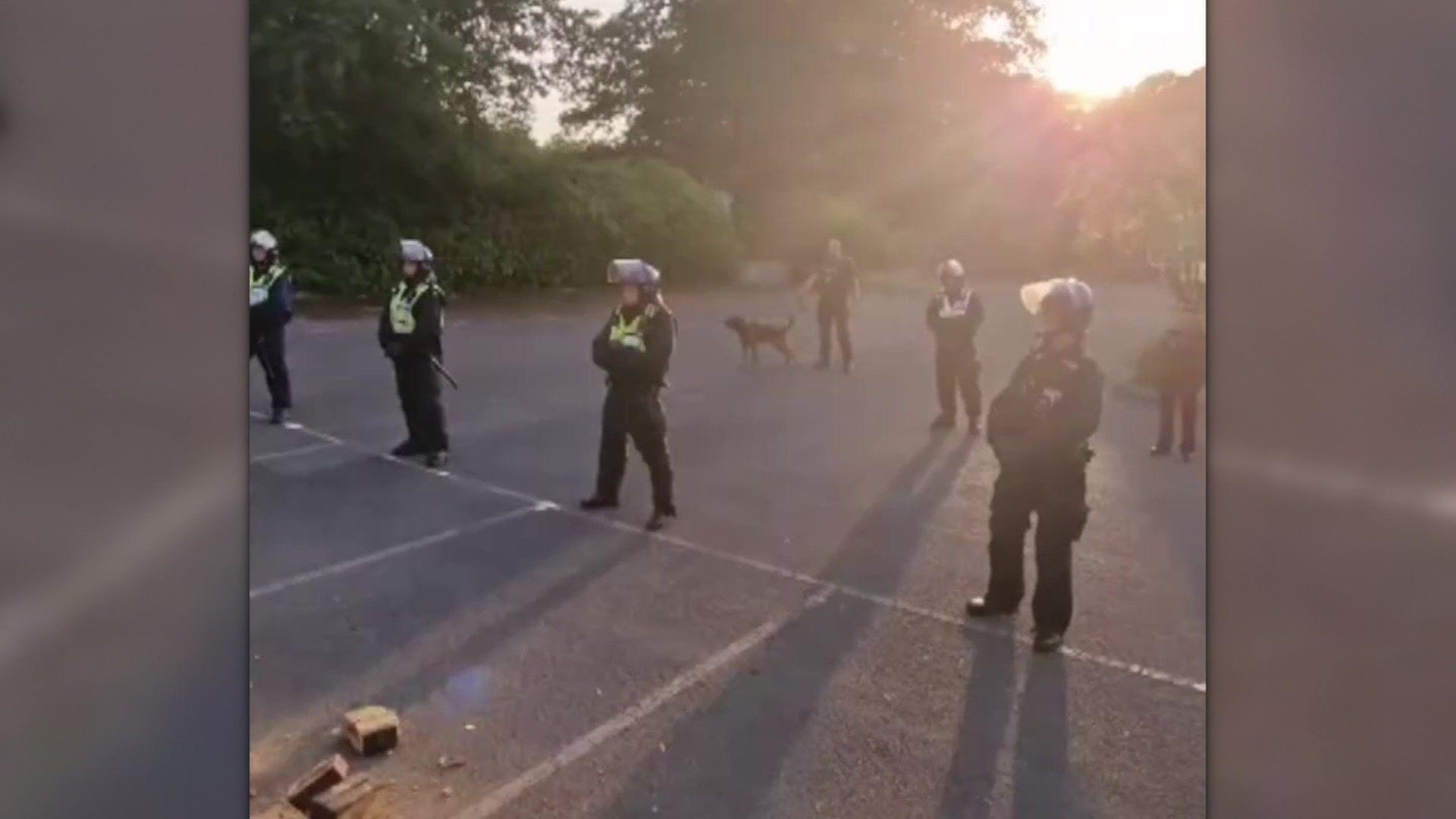 Police in riot gear standing in a row in a car park